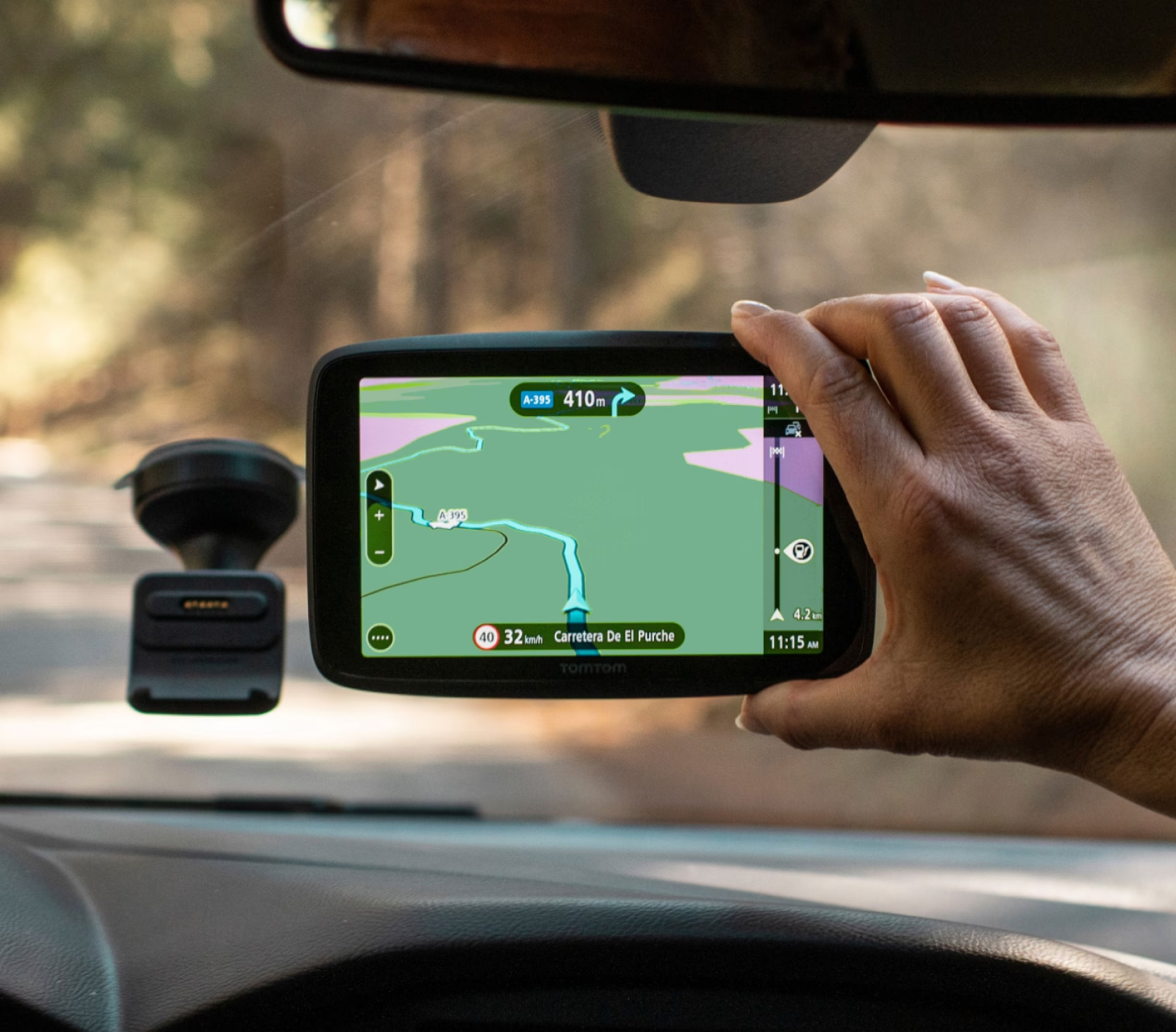 Mano che tiene un dispositivo GPS in un'auto. Lo schermo mostra una mappa con un percorso.