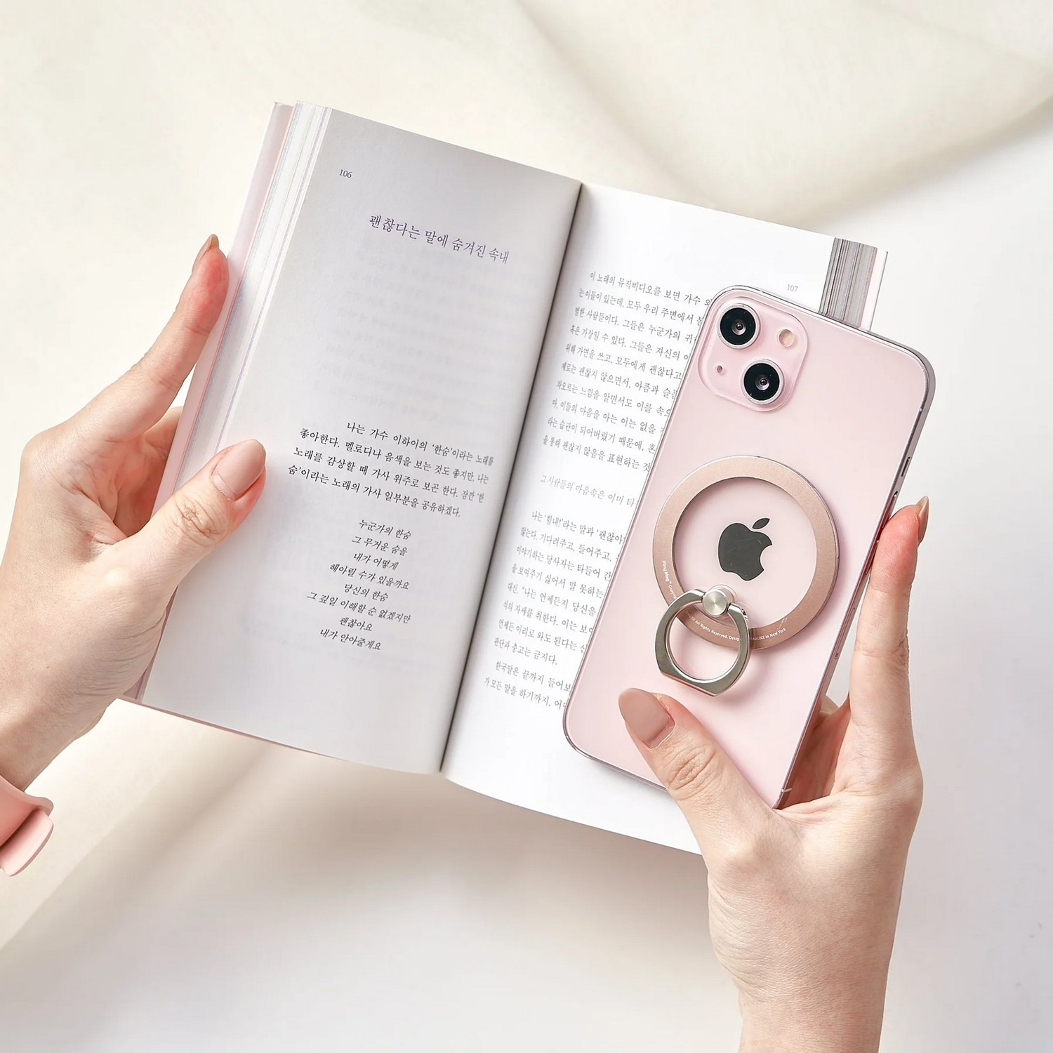 Une femme tenant un livre et un téléphone rose avec un support d'anneau.