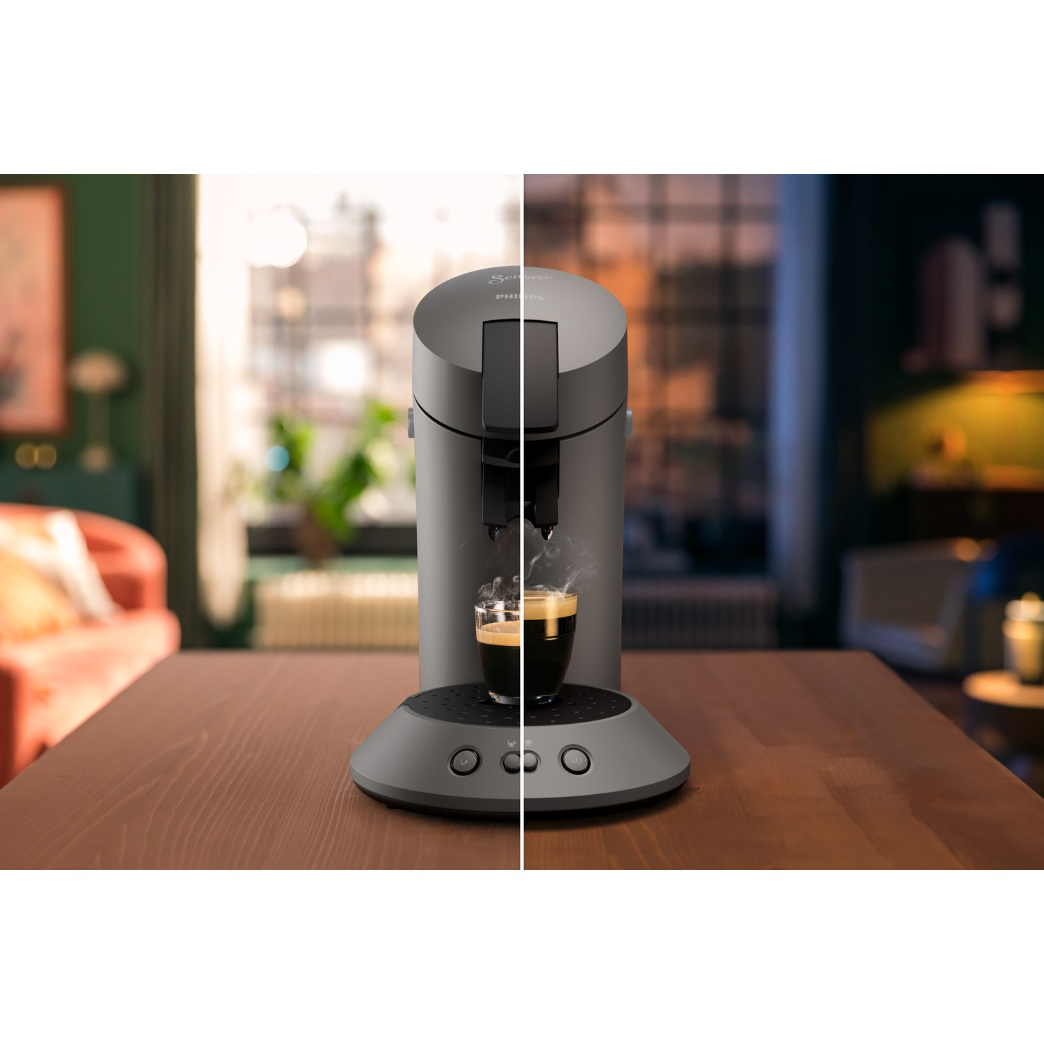 A coffee machine brewing espresso. The machine is grey, with a glass cup. Wooden table with a blurred living room in the background.