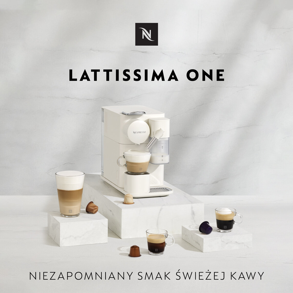 Ekspres Nespresso Lattissima One, biały. Kawa jest serwowana w filiżankach. Białe tło, marmurowa faktura.