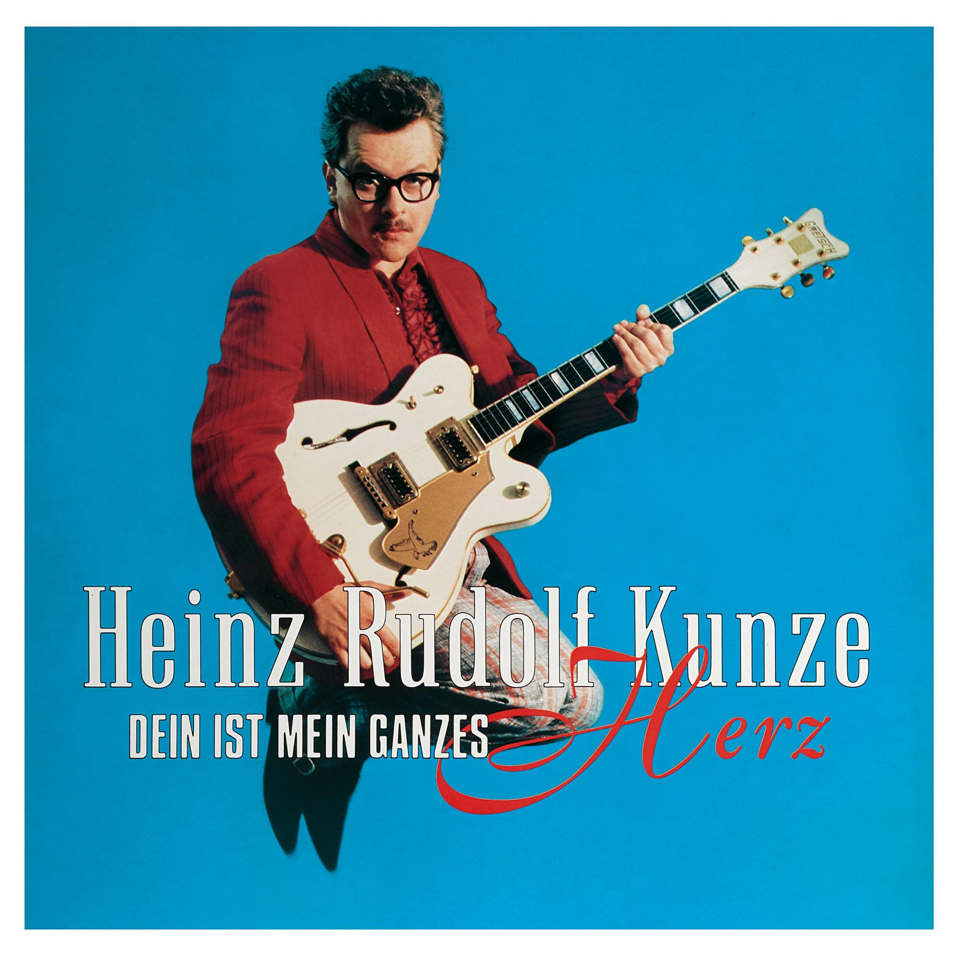 Albumcover mit einem Mann in rotem Anzug, der eine weiße Gitarre spielt.