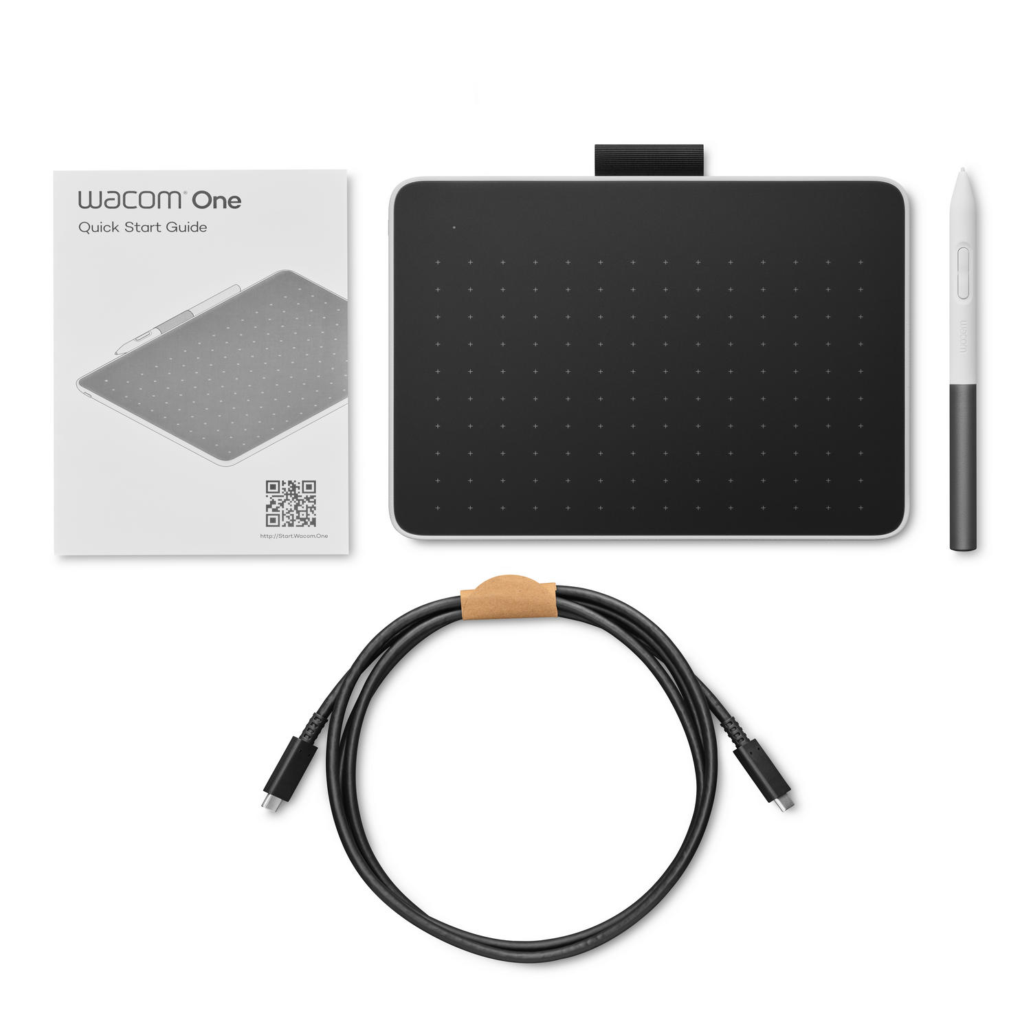 Wacom One drawing tablet, pen, cable and a guide, all on white background.
