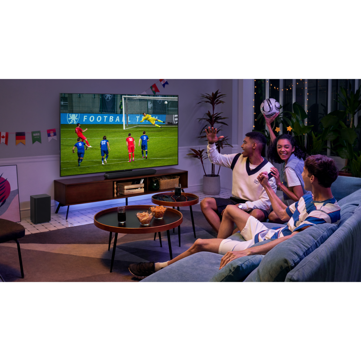 Four friends watching football on TV, with snacks. A large TV shows the game. Cozy living room setting.