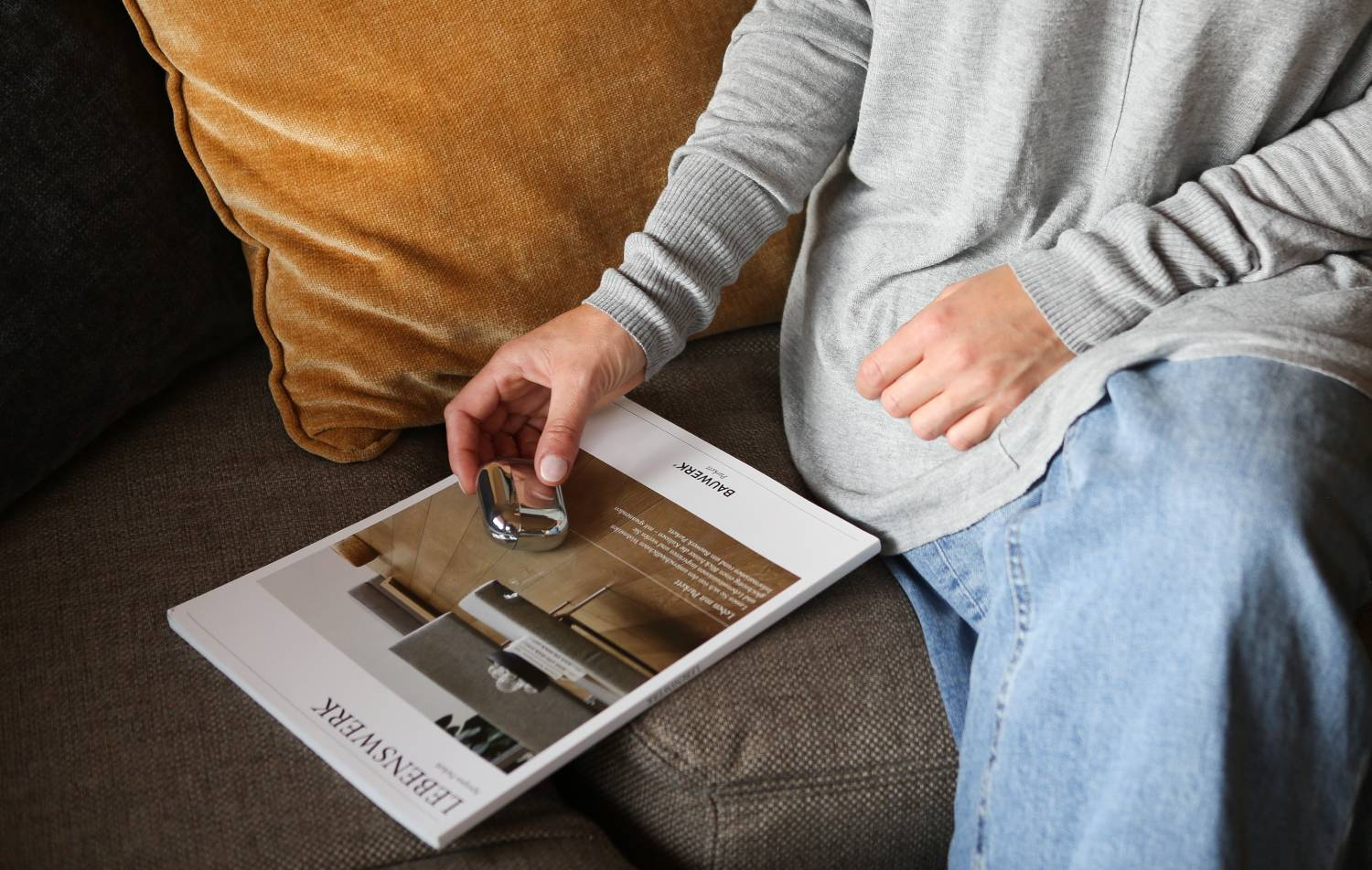 La mano de una persona sosteniendo una manija de puerta cromada sobre una revista.