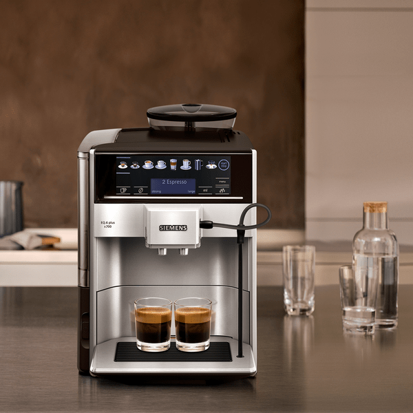 Mutfakta iki fincan kahve ve su şişeleri ile espresso makinesi.