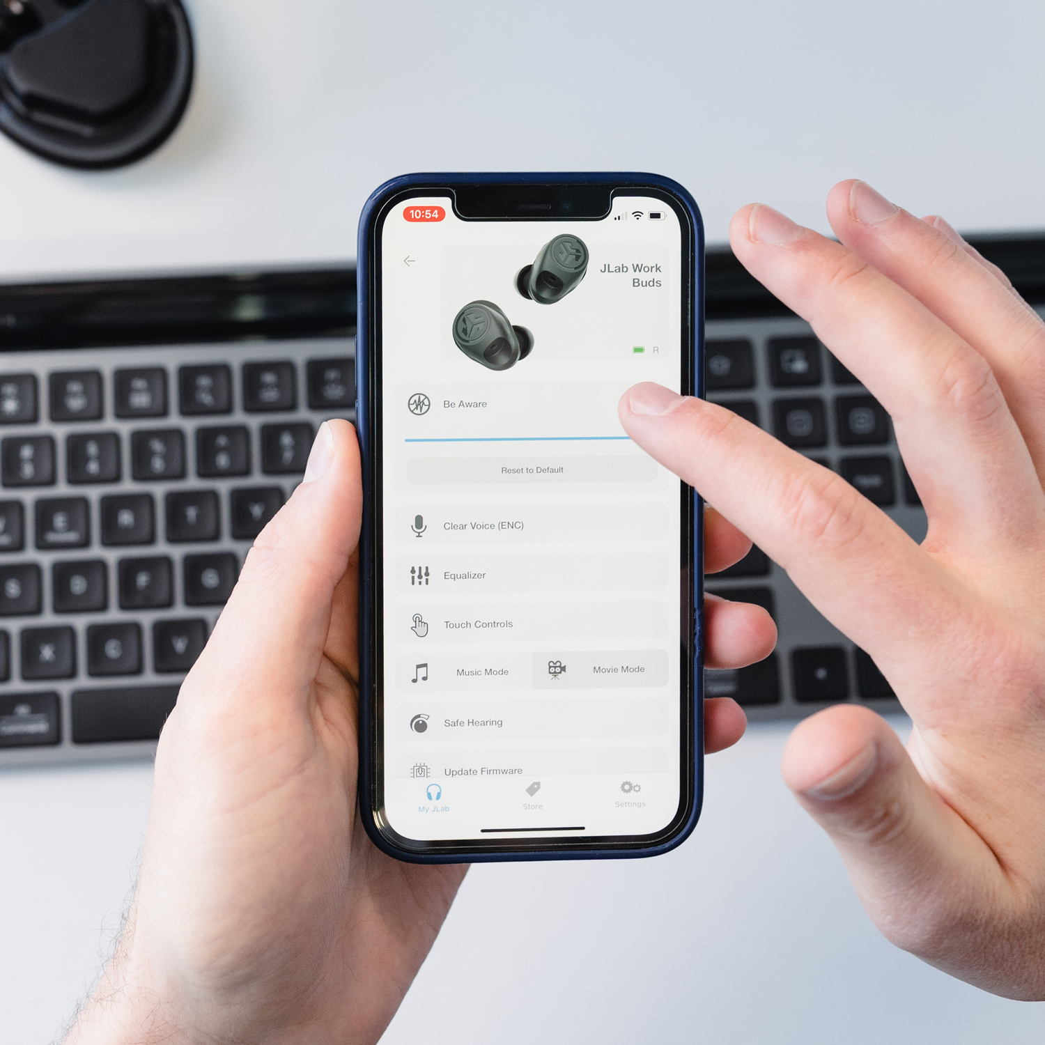 Een persoon houdt een telefoon vast met oordopjes op het scherm. Het scherm toont de app-interface.
