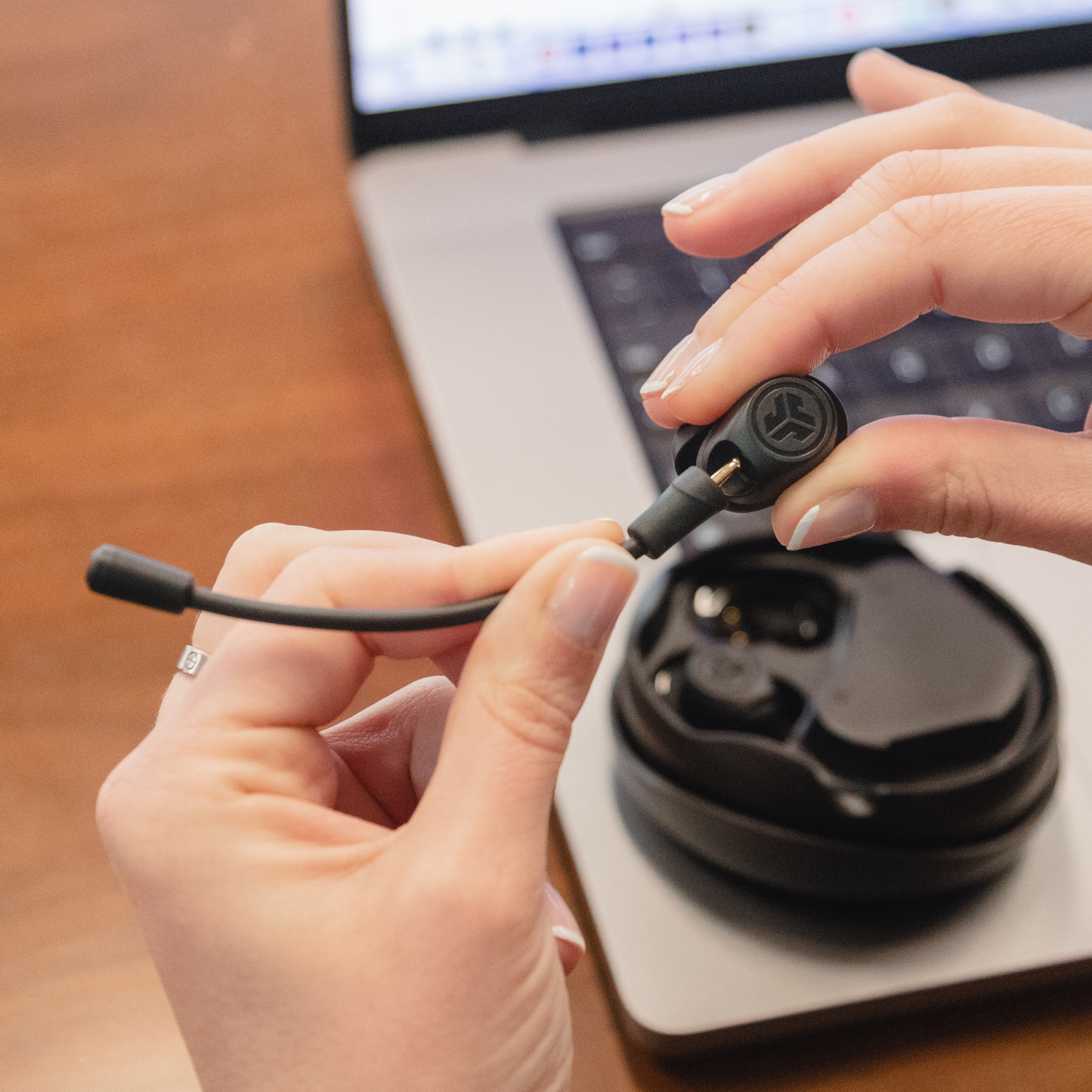 Handen verbinden een kleine microfoon met een Jabra draadloze oordopjes case.