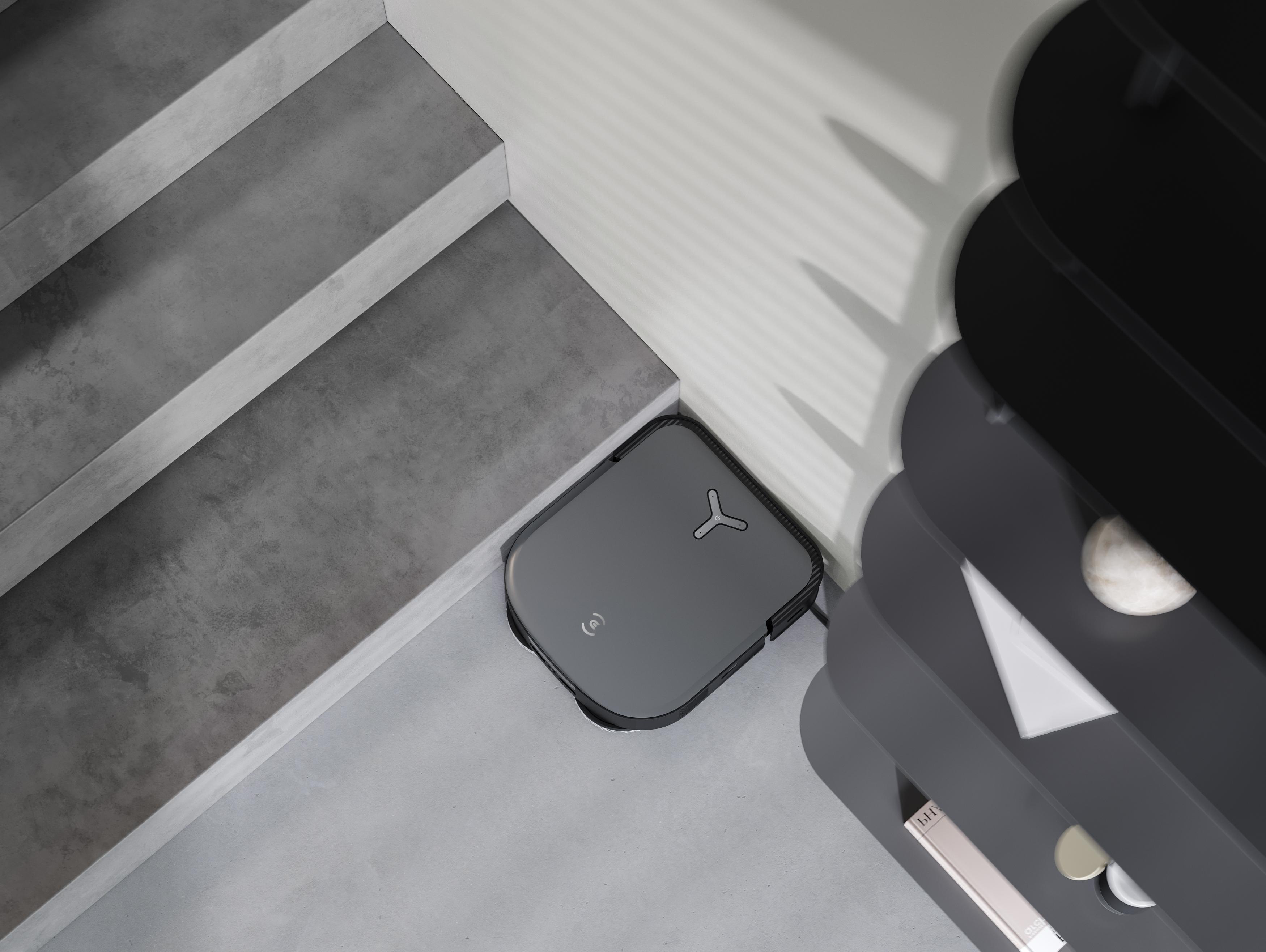 Ein grauer Roboter-Staubsauger sitzt in einer Ecke neben Regalen, von oben betrachtet.