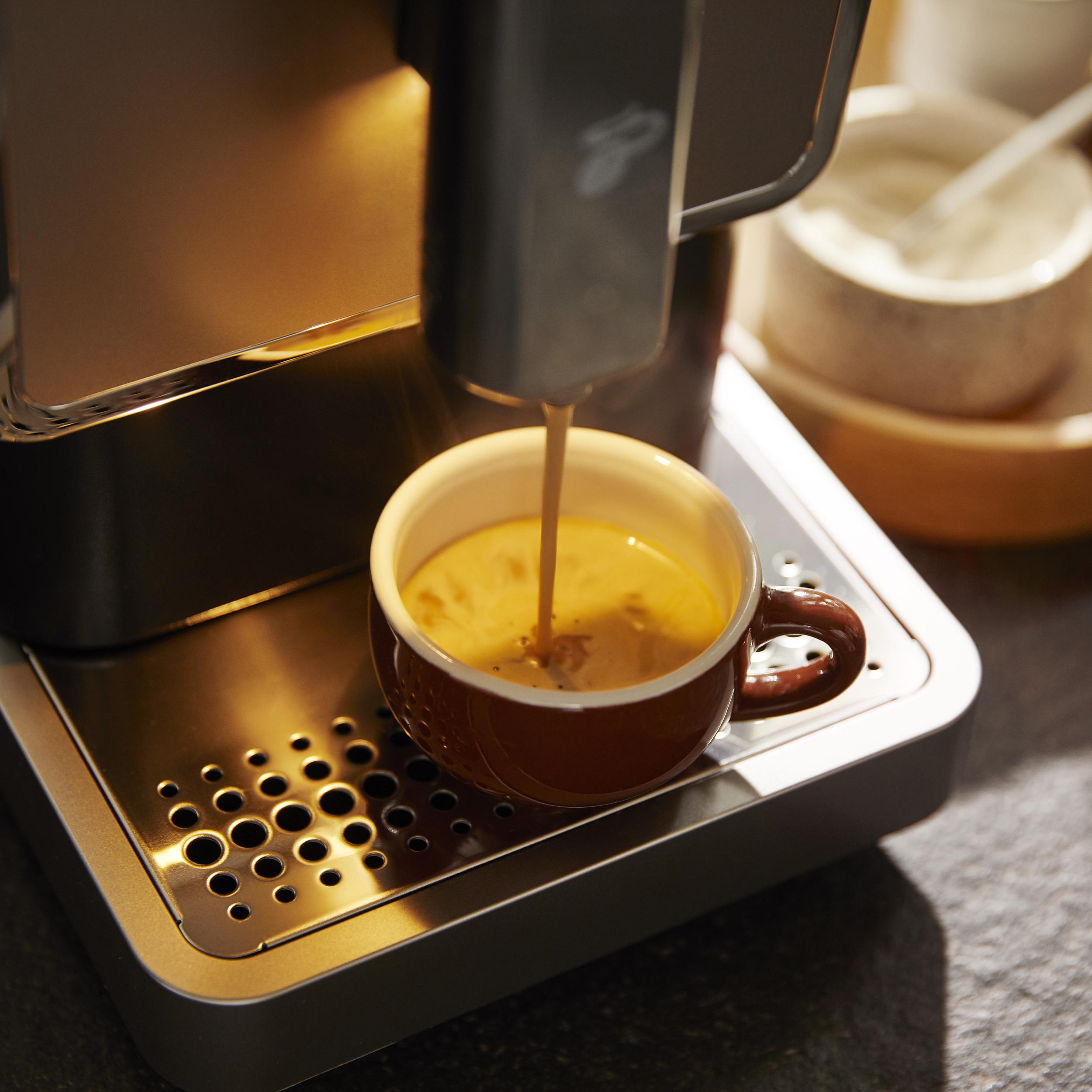 Espressomaschine, die Kaffee in eine braune Tasse gießt. Edelstahl-Tablett und Hintergrund.