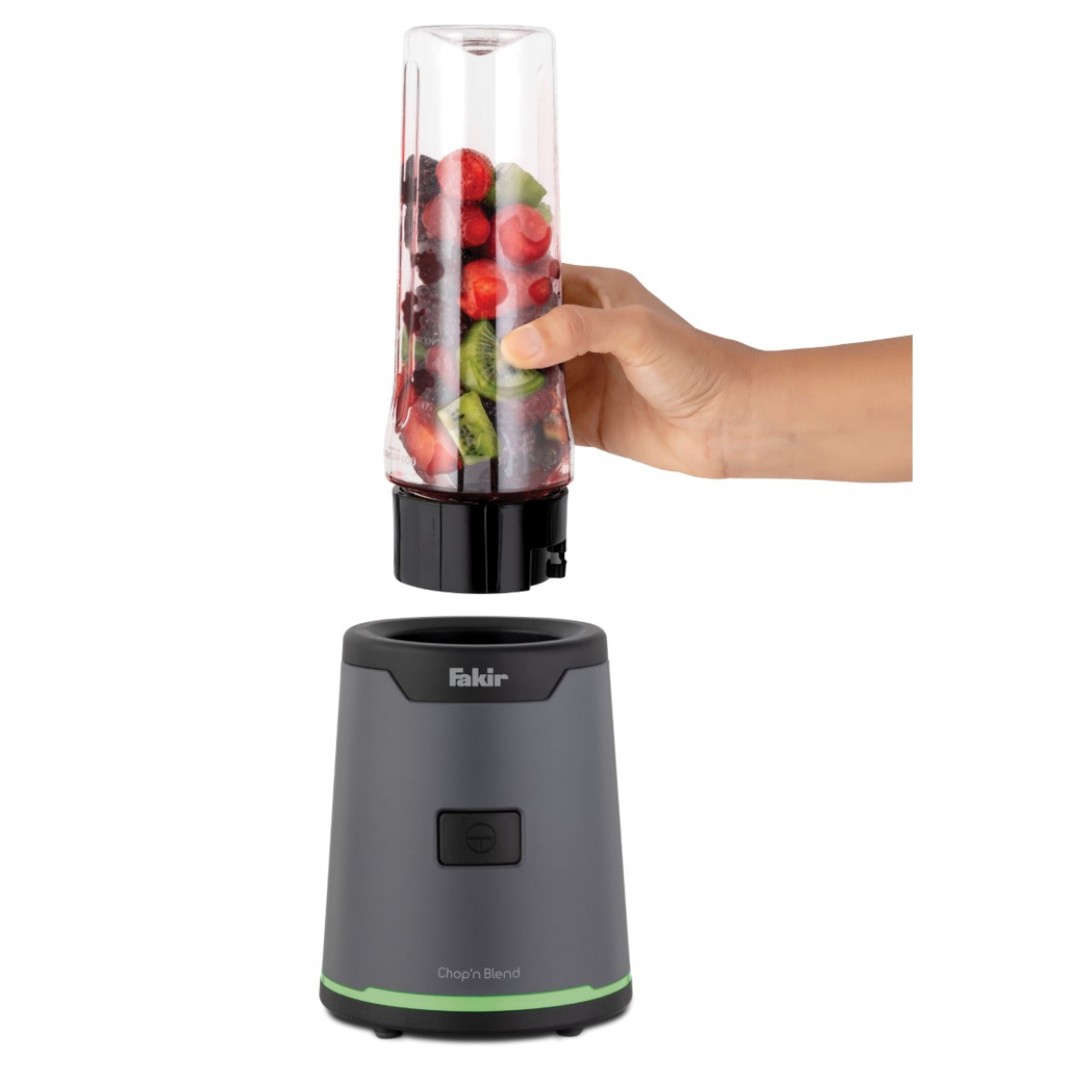 Bir el, beyaz arka planda gri bir Fakir blender tabanı üzerinde meyve dolu bir blender kabı tutuyor.