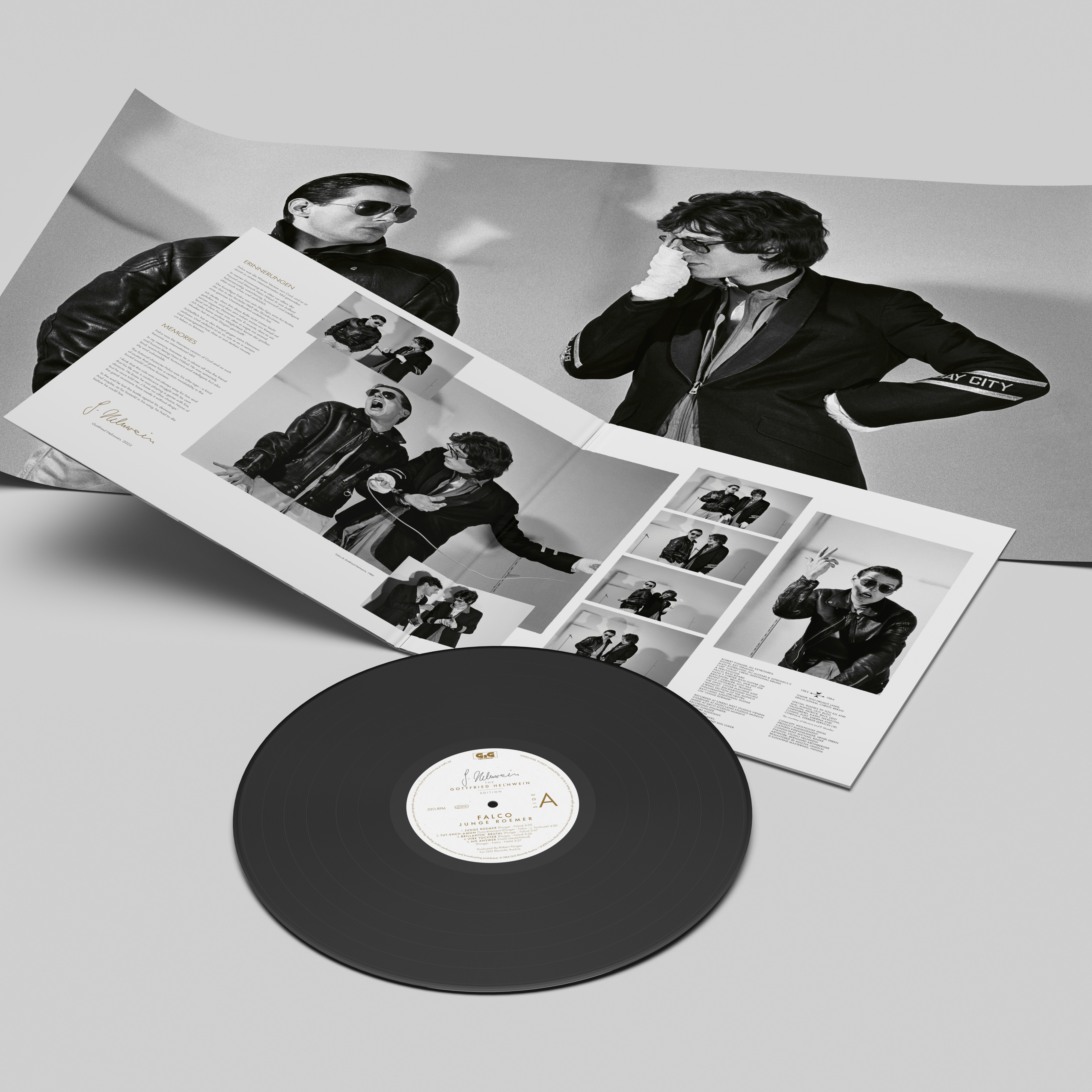 Zwei Männer mit Sonnenbrillen betrachten eine Vinylplatte und einen Album-Spread.