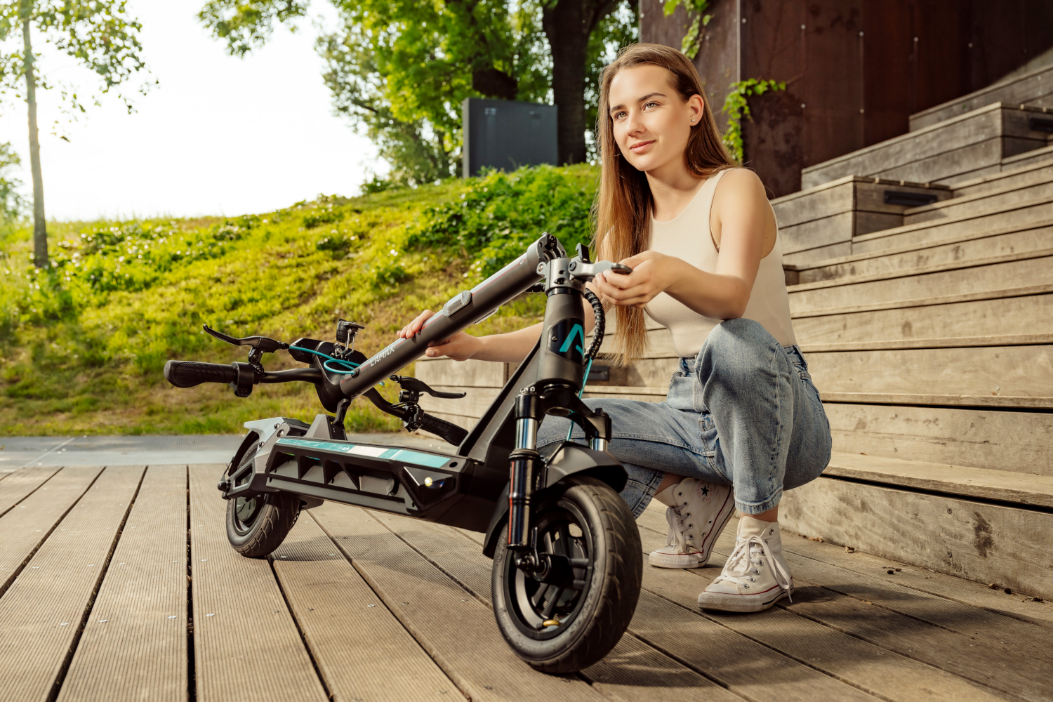 Nő guggol egy elektromos roller mellett a fa fedélzeten.