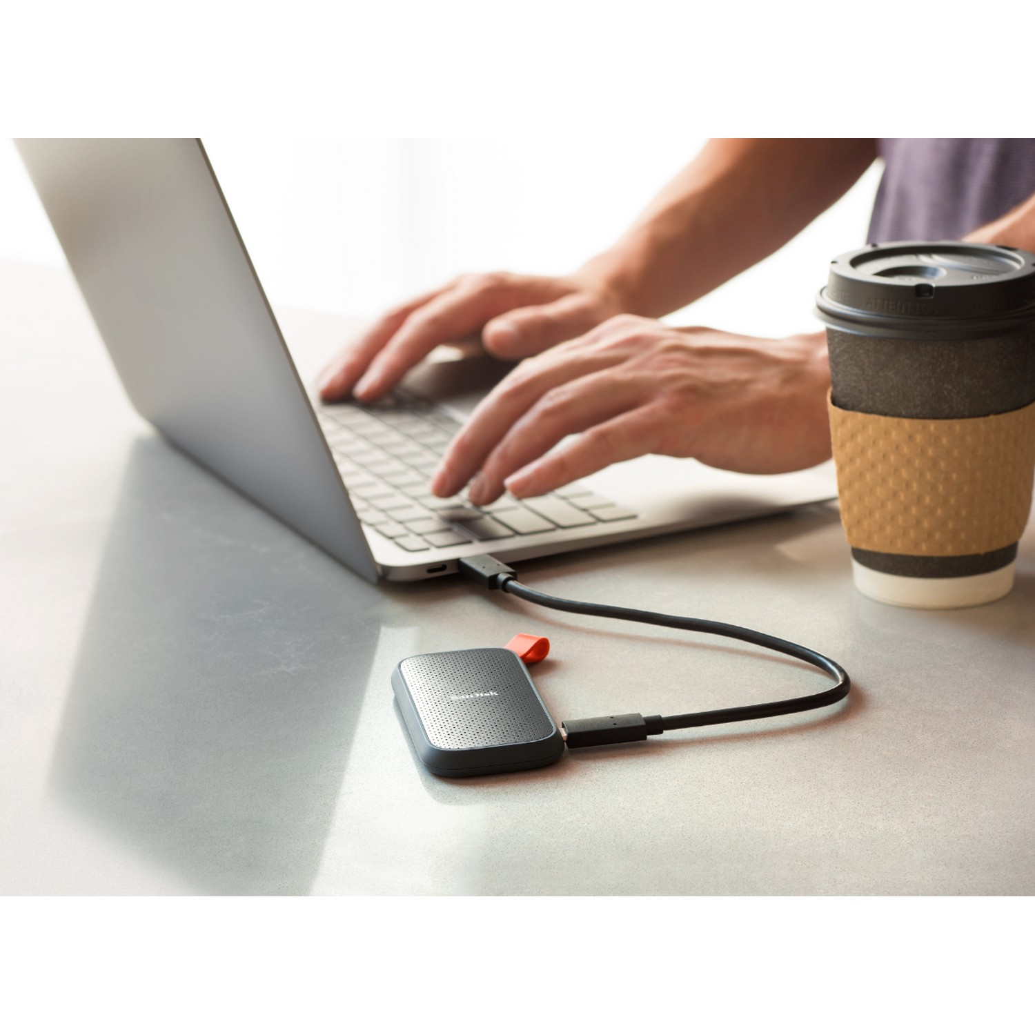 Una persona usando una laptop, con un disco duro portátil conectado a ella.