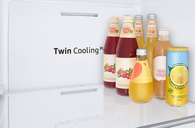 Wnętrze lodówki z kilkoma butelkami soku i napojów gazowanych na białej półce.