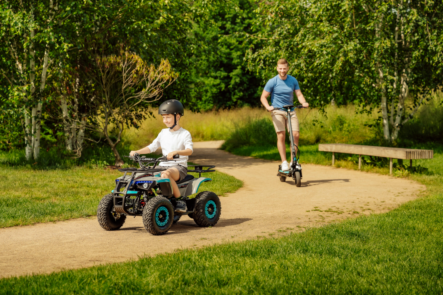 Egy fiú egy kis ATV-vel, egy férfi pedig elektromos robogóval parkban.