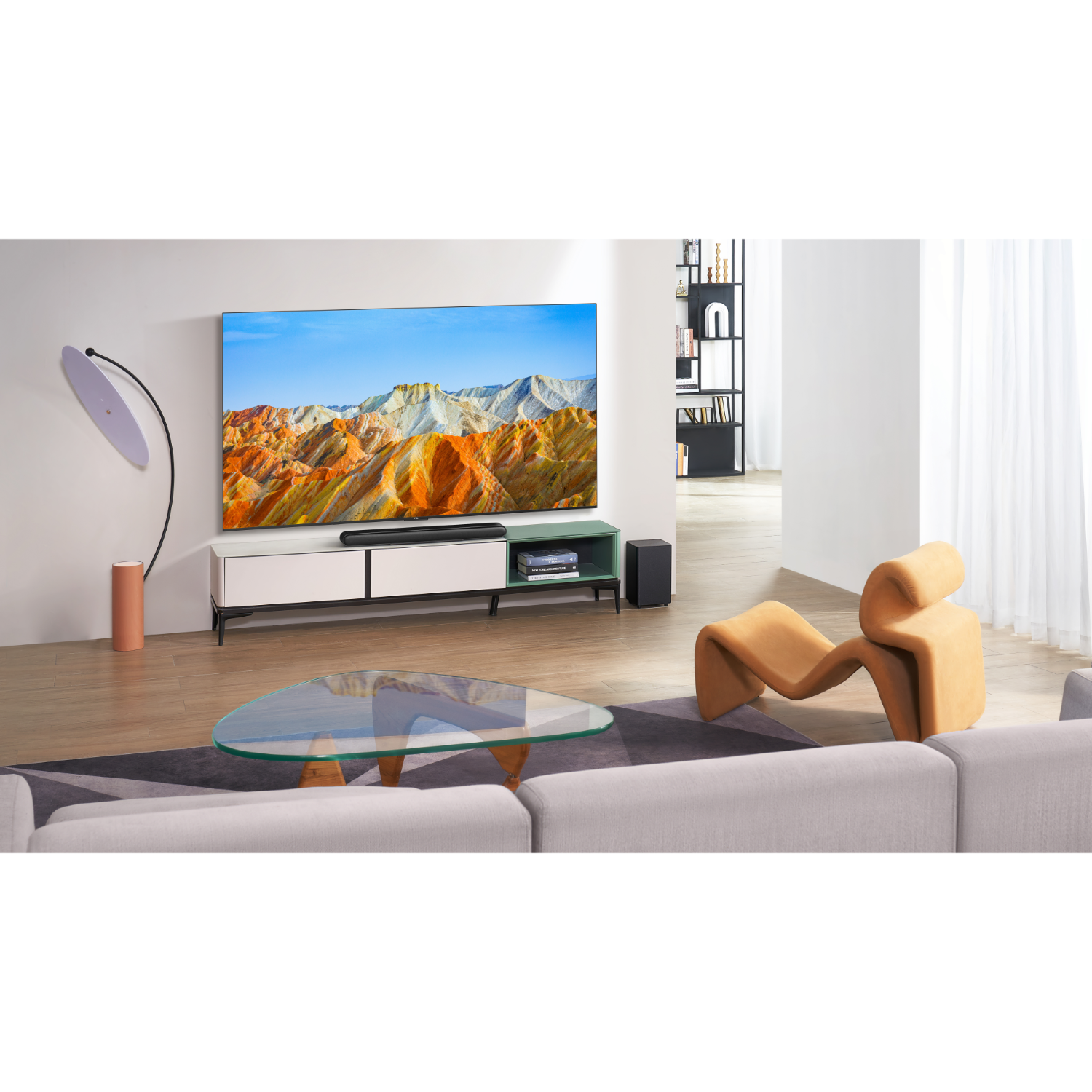 Woonkamer. TV met bergen, soundbar, bank, salontafel en een lamp.