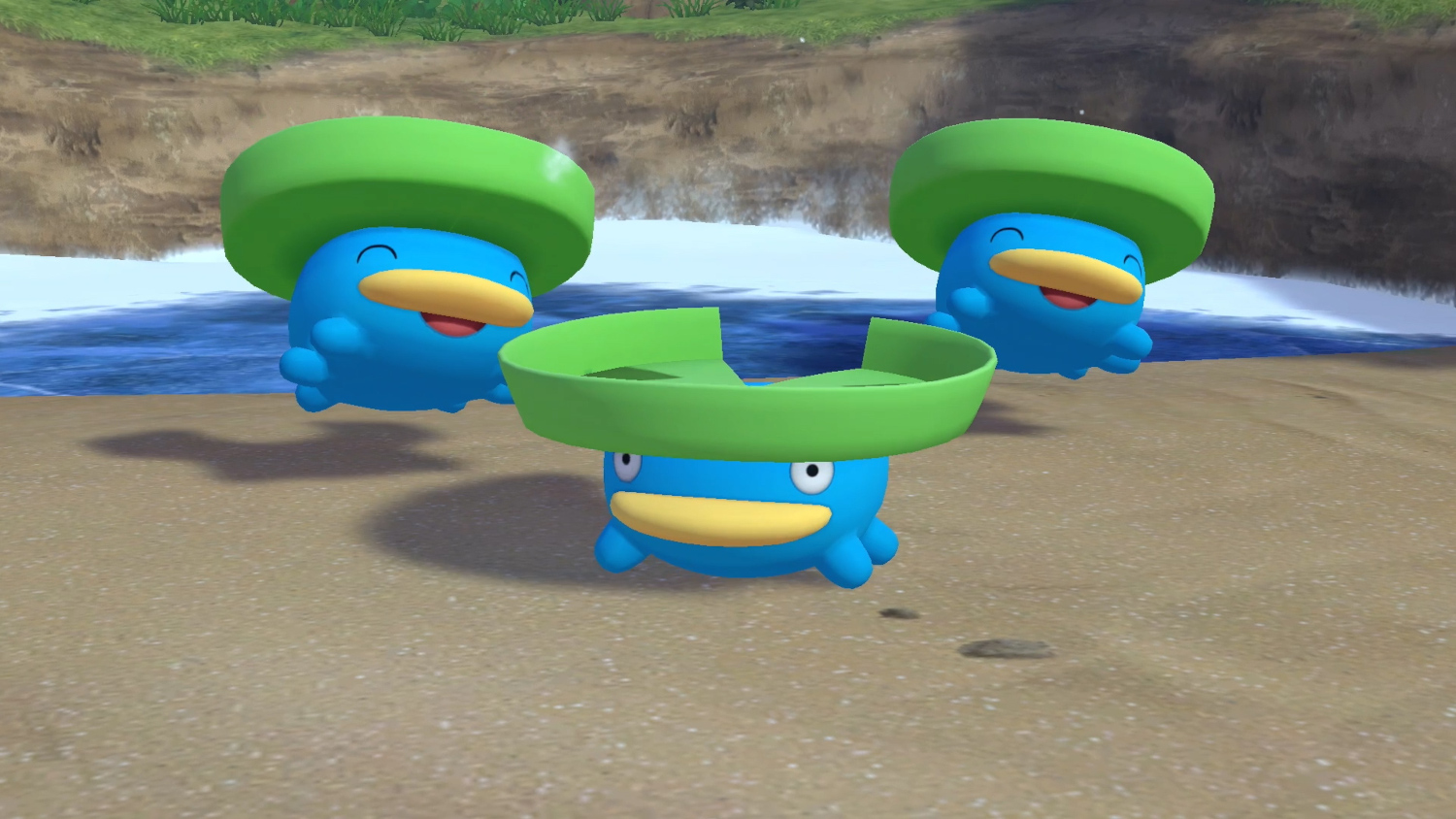 Drie blauwe Pokémon met groene hoeden zweven boven een zandstrand en een watermassa.
