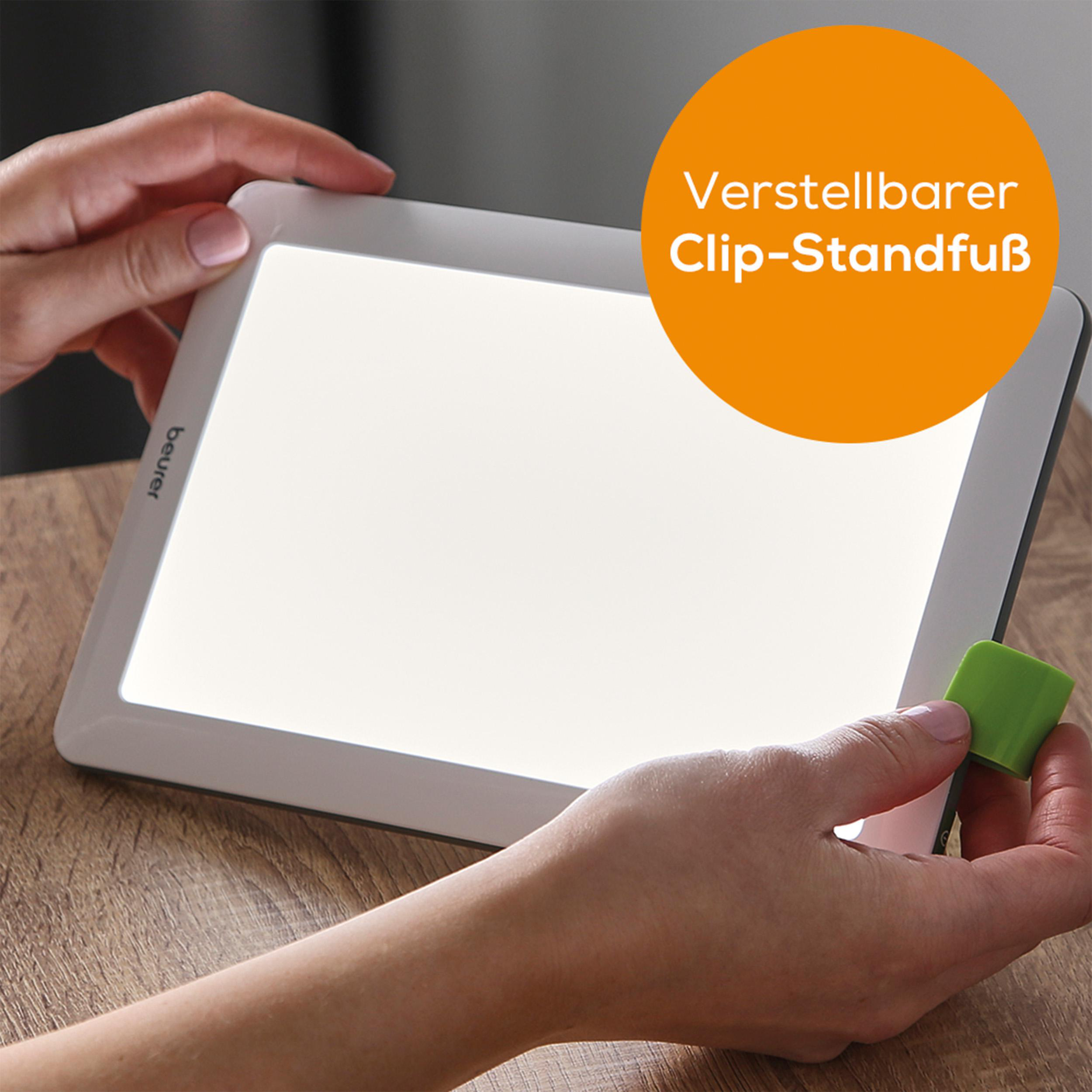Hände halten helle Lichttherapielampe; Text: 'Verstellbarer Clip-Standfuß'.