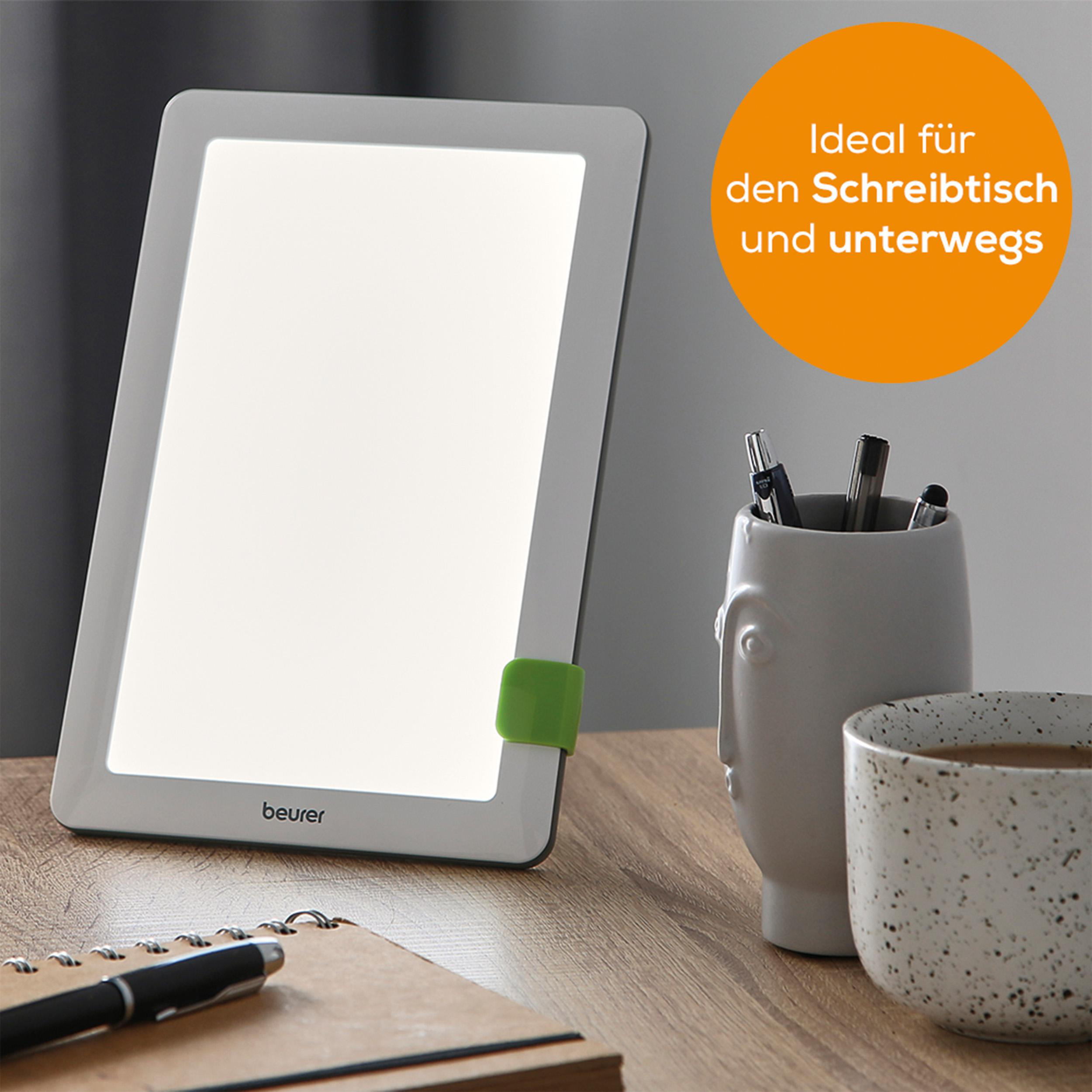 Weiße Lichttherapielampe auf einem Holzschreibtisch. Inklusive Stifthalter und Tasse.
