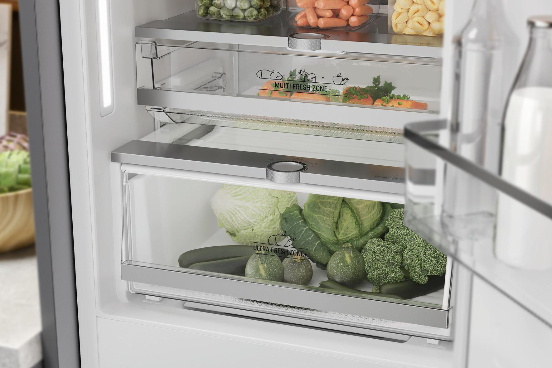 Kühlschrankinnenraum mit Gemüseschubladen mit Salat, Brokkoli und Karotten.