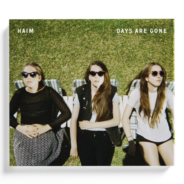Albumcover von HAIMs "Days Are Gone". Drei Frauen mit Sonnenbrillen liegen auf Liegestühlen im Gras.
