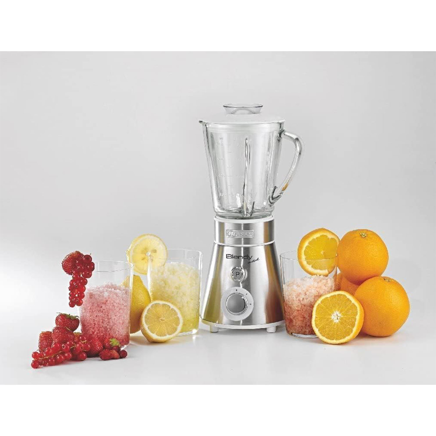 Frullatore con frutta e bevande. Include arance, bacche e limoni. Sfondo bianco.