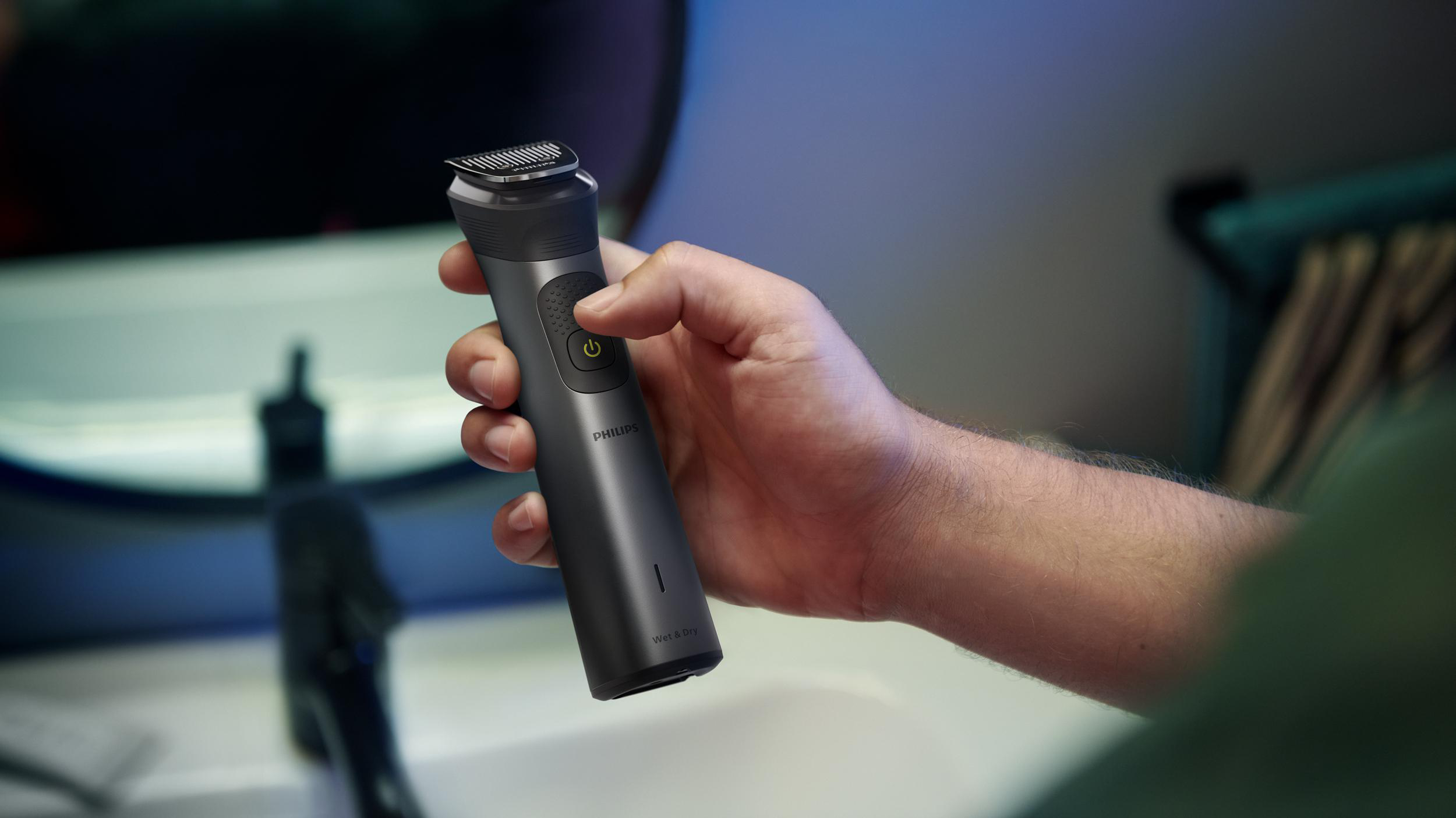 Die Hand einer Person, die einen schwarzen und silbernen elektrischen Rasierer von Philips hält.