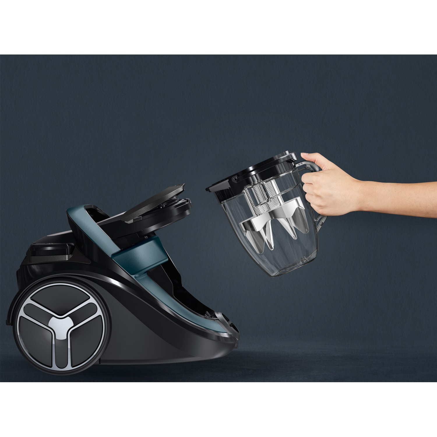 Vacuum cleaner with detached dust container. The container is being held by a person's hand.