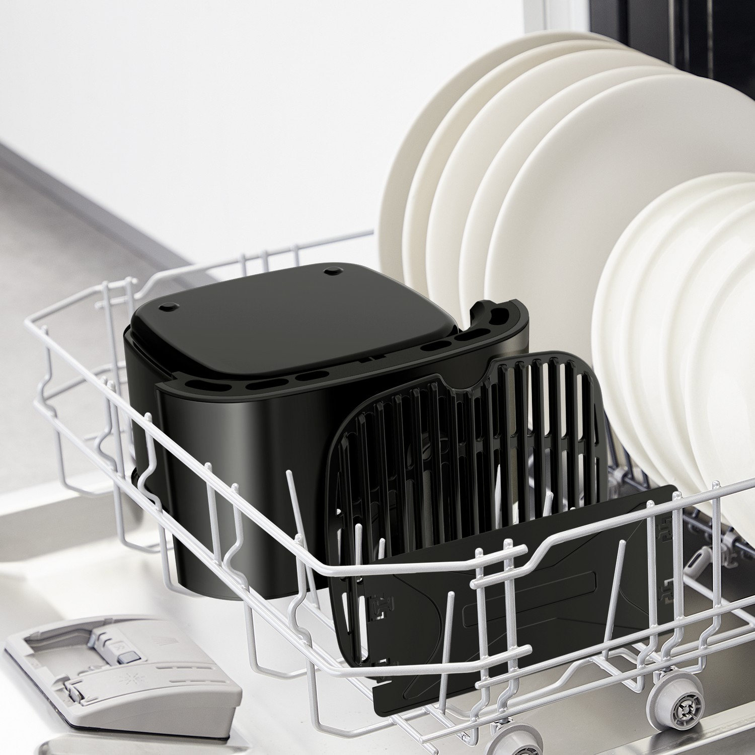 Zwarte airfryer onderdelen in vaatwasserrek met witte borden.