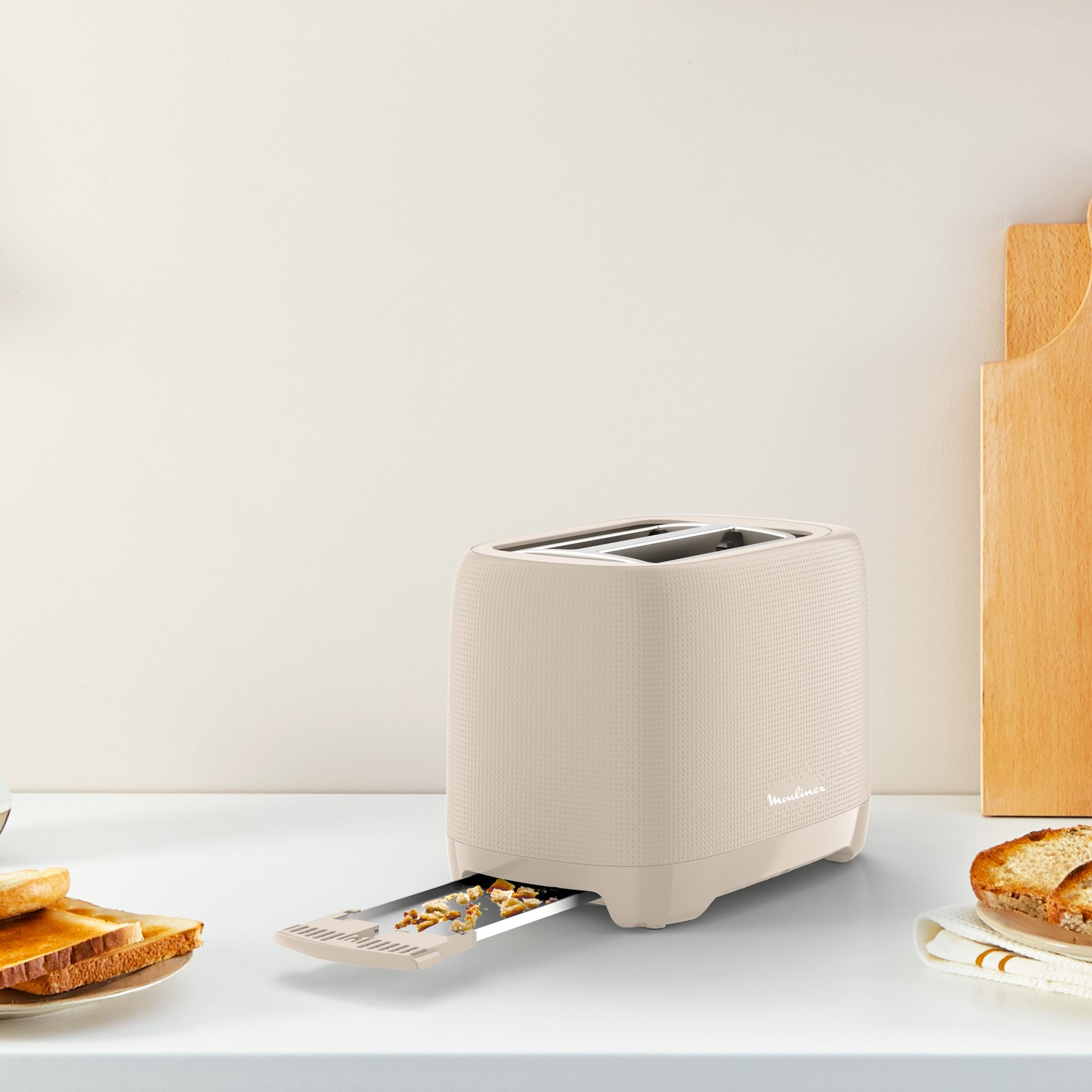 Beige toaster with a slice of bread in the slot and another next to it.