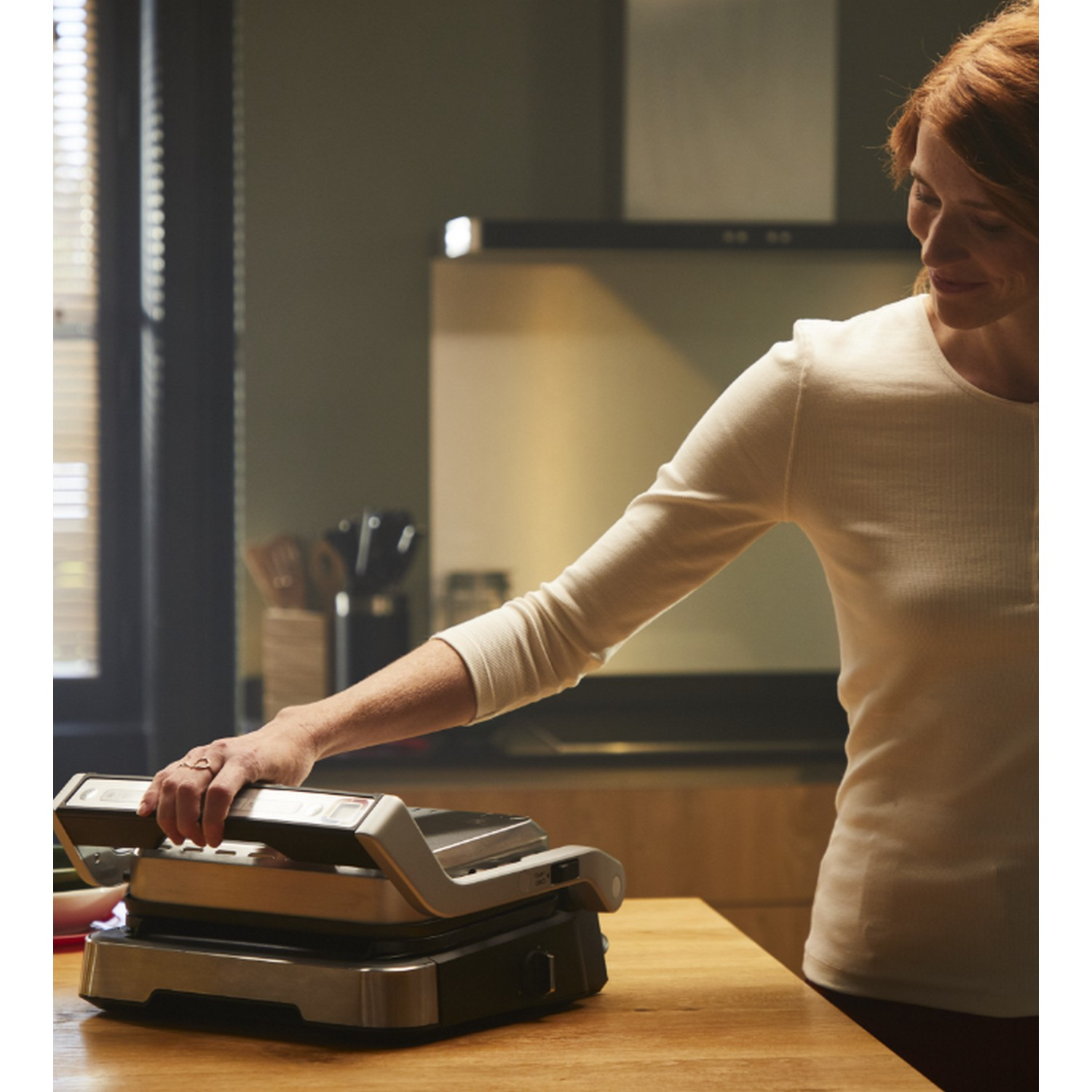 Vrouw in een keuken die een grill op een houten aanrecht gebruikt.
