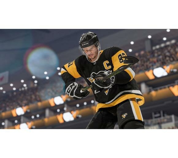 Hokeista w czarno-żółtym stroju podczas meczu, trzymający kij hokejowy.