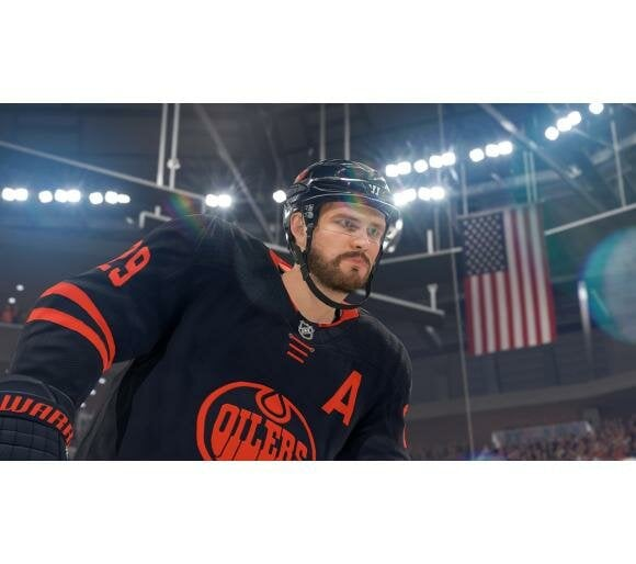 Hokeista w koszulce Oilers, jeżdżący na lodzie. Amerykańska flaga w tle, na stadionie.