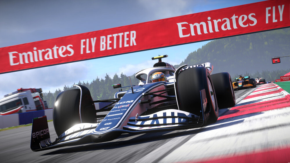 Samochód wyścigowy Formuły 1 na torze, z kierowcą i banerem z napisem 'Emirates Fly Better'.