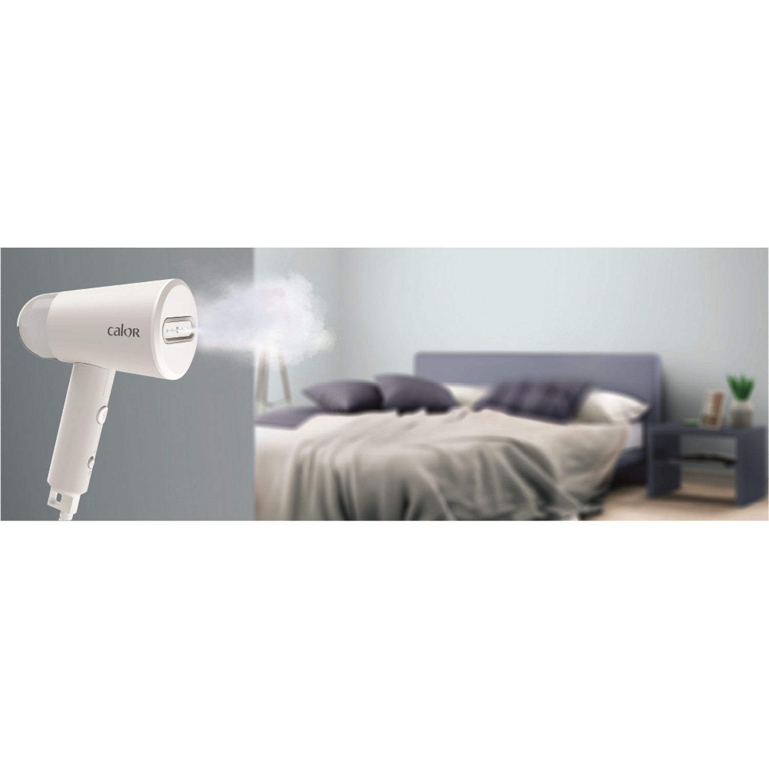 Witte handheld steamer met stoom die eruit komt. Achtergrond: een bed met kussens en een grijze muur.