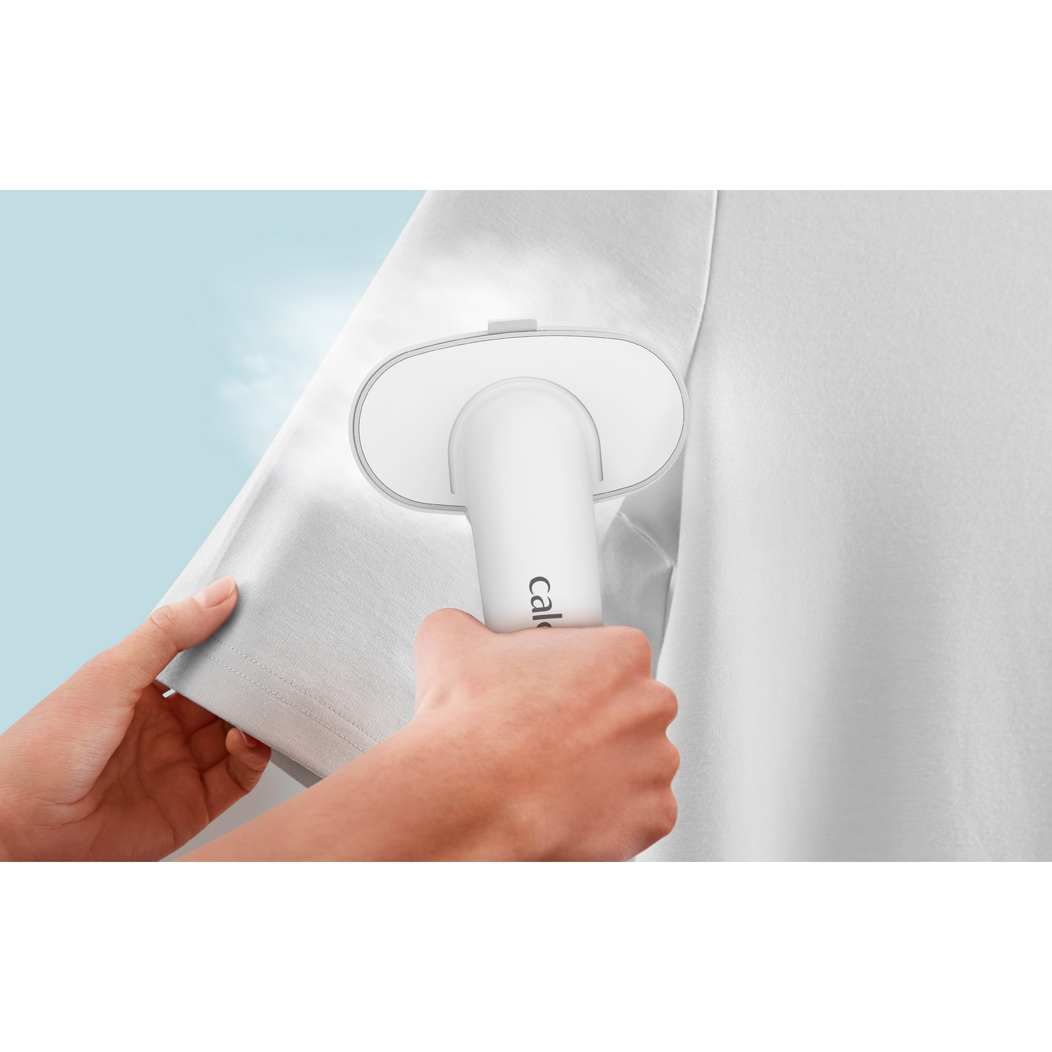 A white clothes steamer steaming a white shirt sleeve.