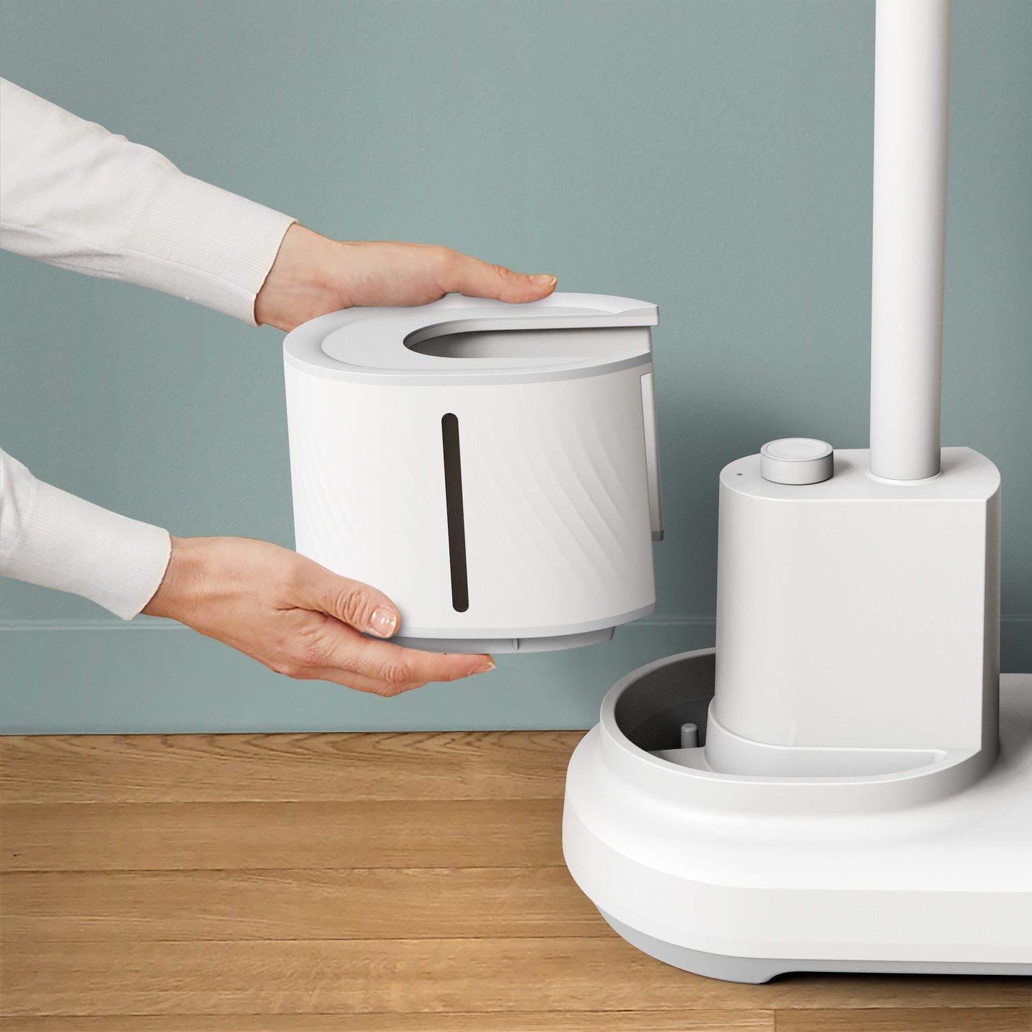 Hands placing a white cylindrical part into a white base of a white fan.
