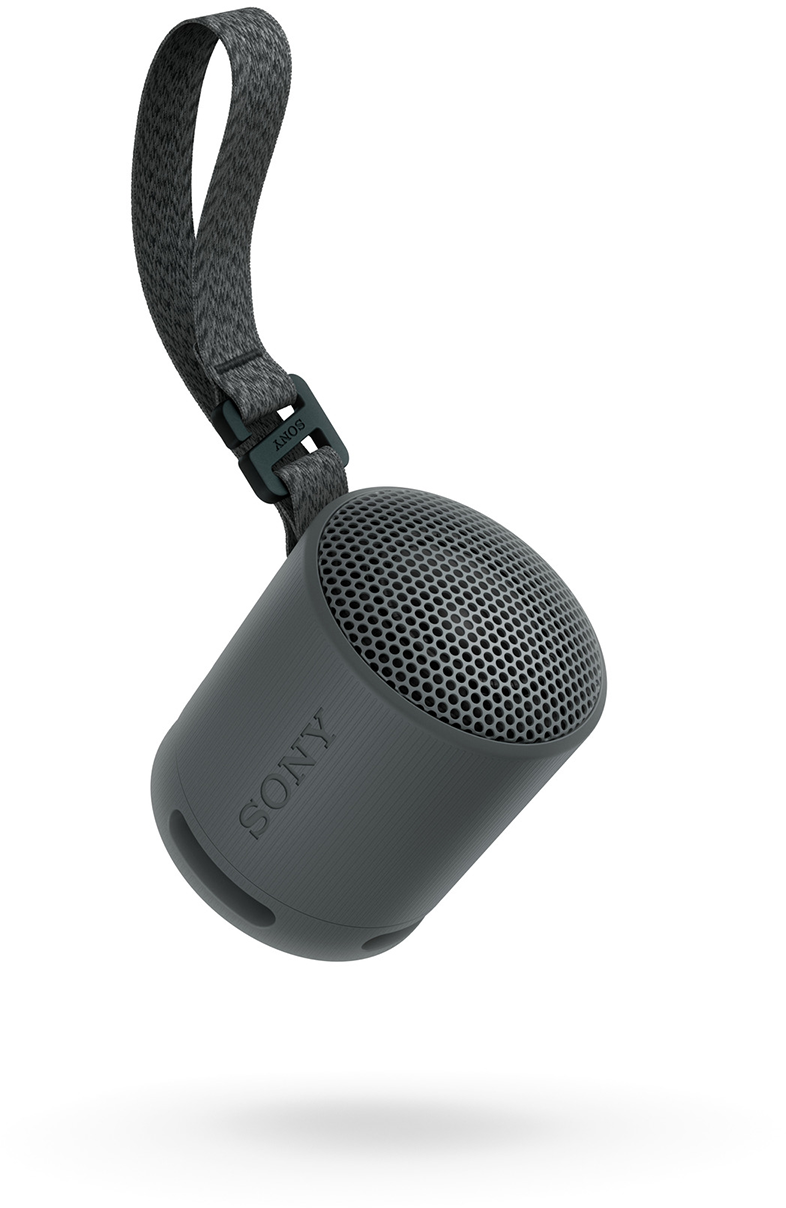 Egy szürke, hengeres Sony hangszóró fekete pánttal. A levegőben lóg.