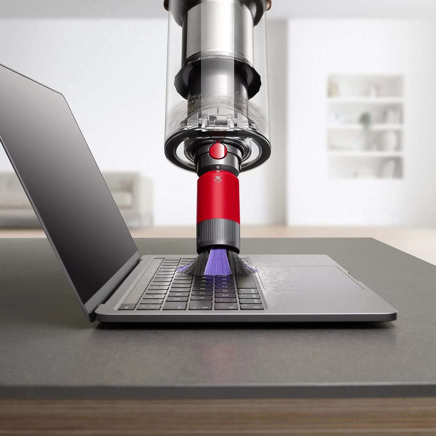 Een stofzuiger maakt een laptoptoetsenbord schoon. Stof en vuil zijn zichtbaar.