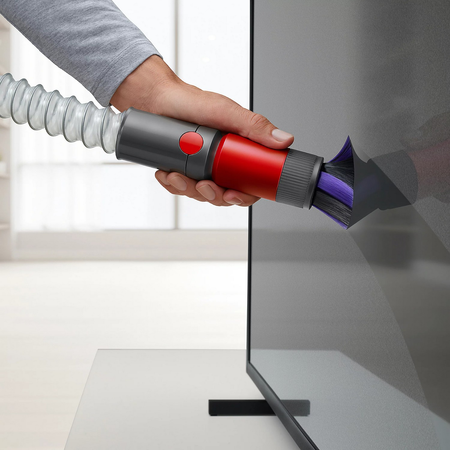 Een persoon die een tv-scherm schoonmaakt met een stofzuiger. Witte achtergrond.