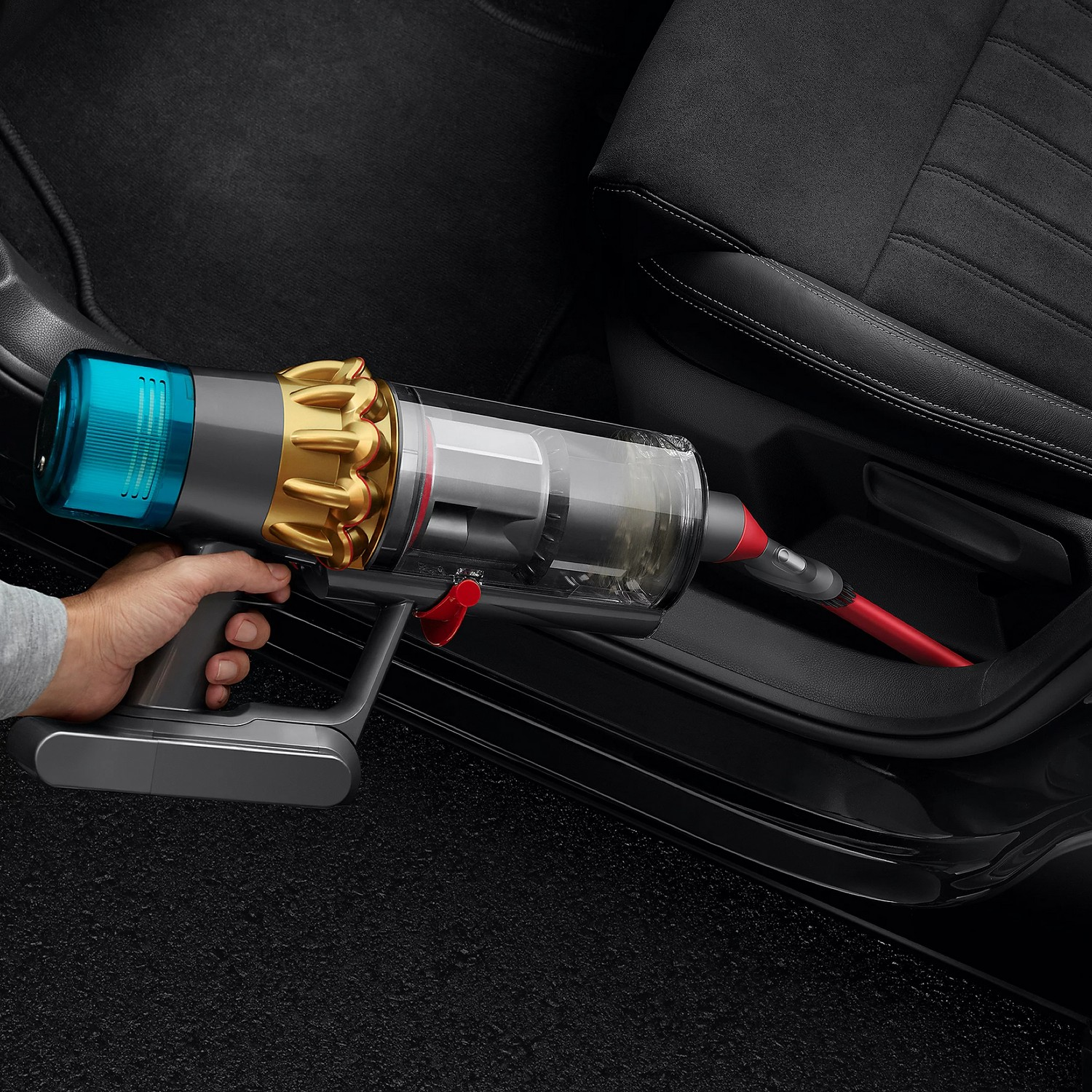 Een persoon die een handstofzuiger gebruikt om een auto-interieur schoon te maken.