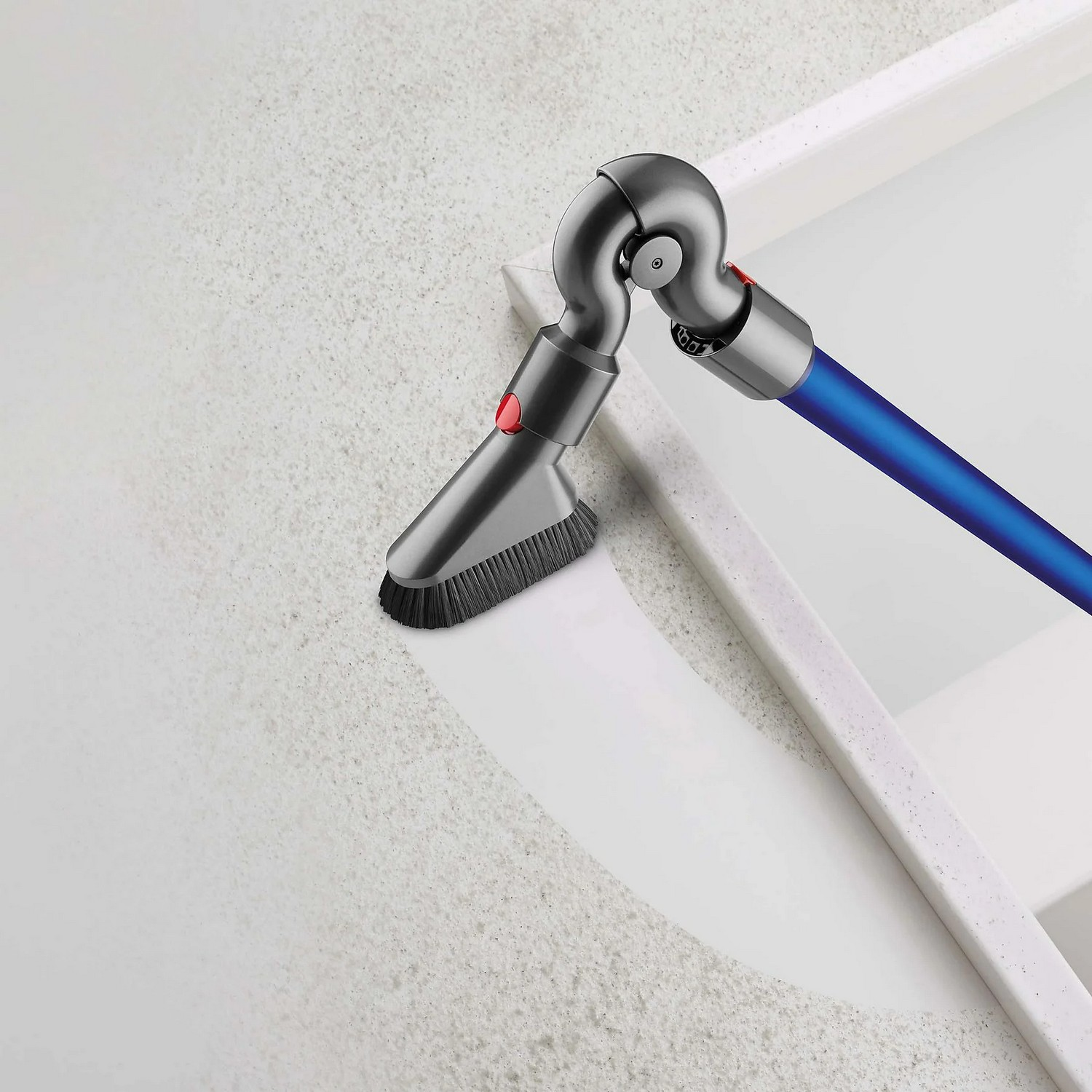 Accessoire d'aspirateur Dyson. Gris et bleu, incliné sur une surface blanche.