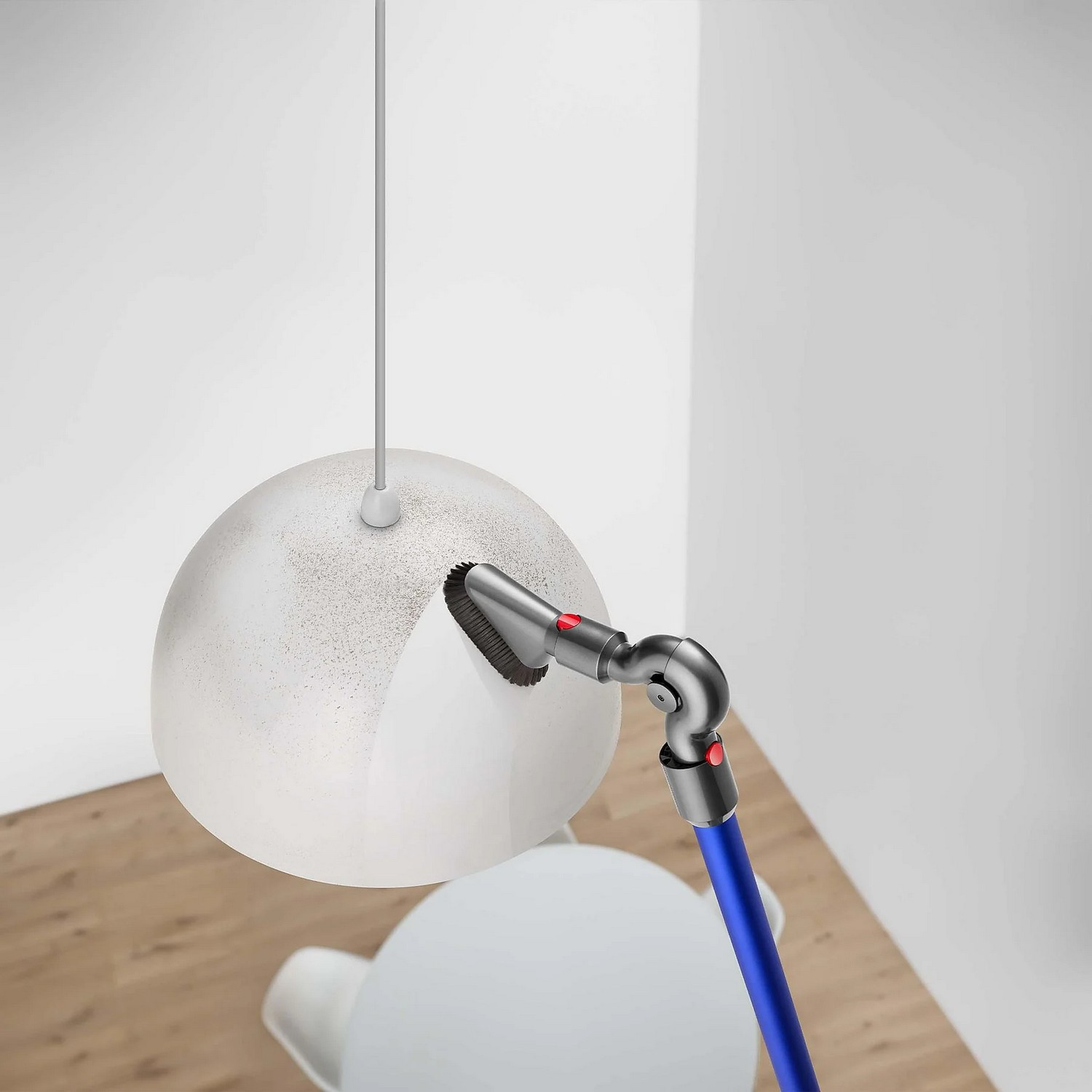 Un aspirateur nettoie un luminaire. Le luminaire est un globe blanc.