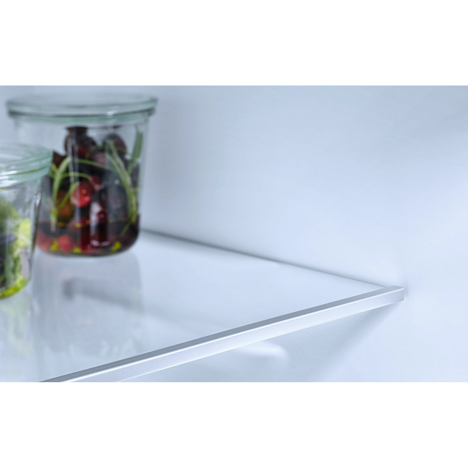 Bocaux en verre remplis de cerises et autres ingrédients sur une étagère blanche avec fond blanc.