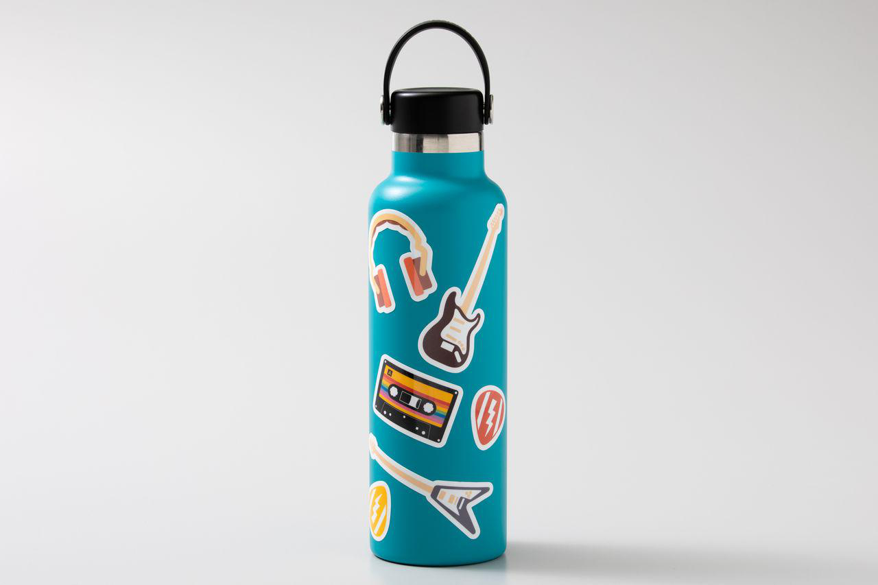 Türkisgrüne Wasserflasche mit Aufklebern von Kopfhörern, Gitarre, Kassette und Blitz.