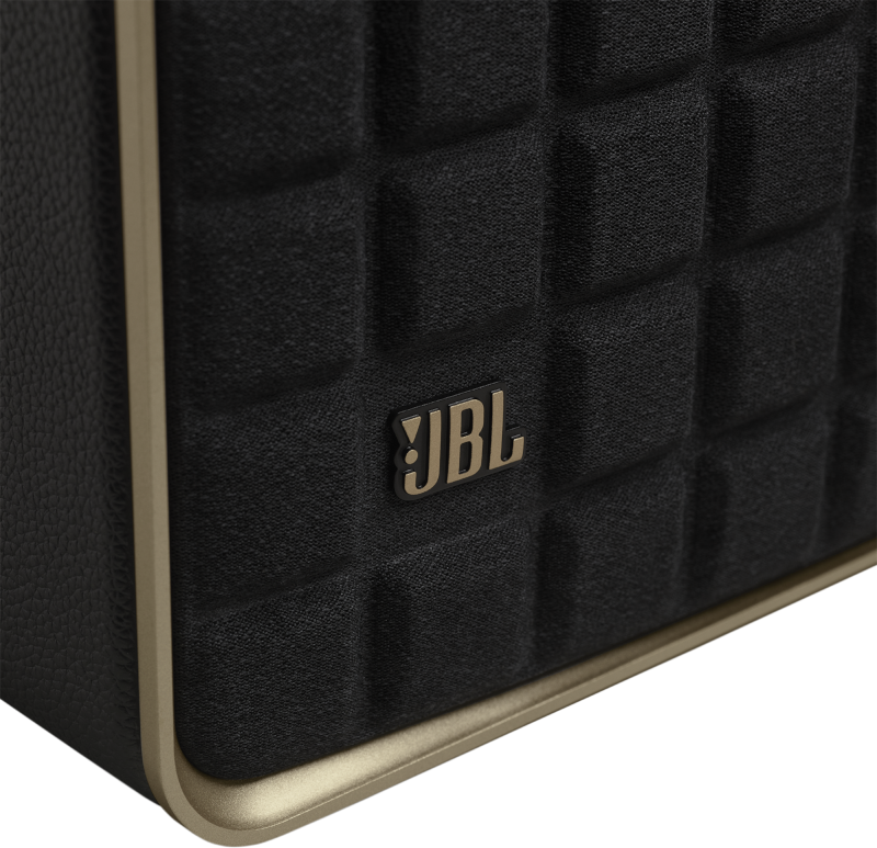 Nahaufnahme eines schwarzen JBL-Lautsprechers. Der Lautsprecher hat eine strukturierte Vorderseite und eine goldfarbene Zierleiste.