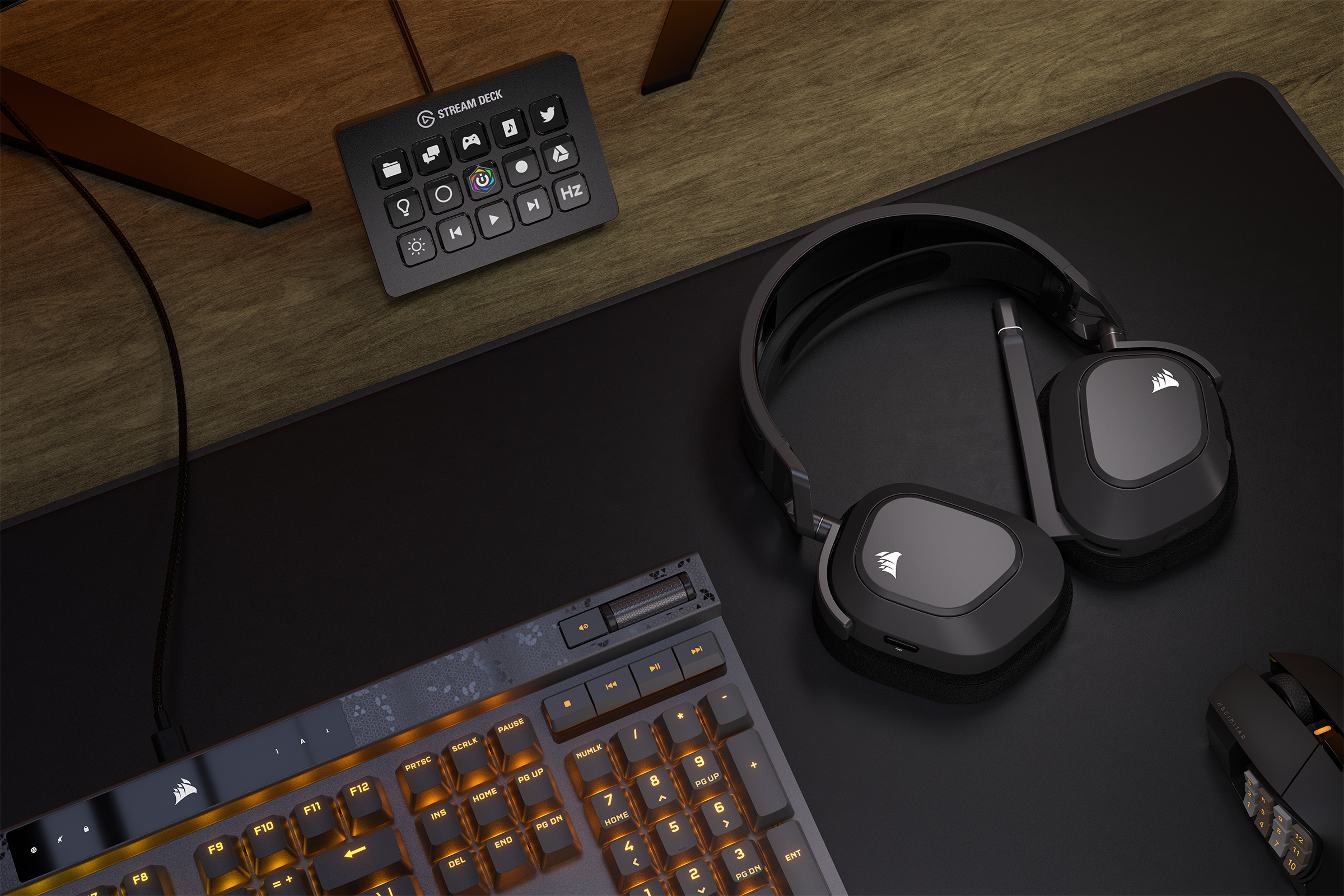 Ein Schreibtisch-Setup mit Tastatur, Kopfhörern und einem Stream Deck, alles auf schwarzer Oberfläche.