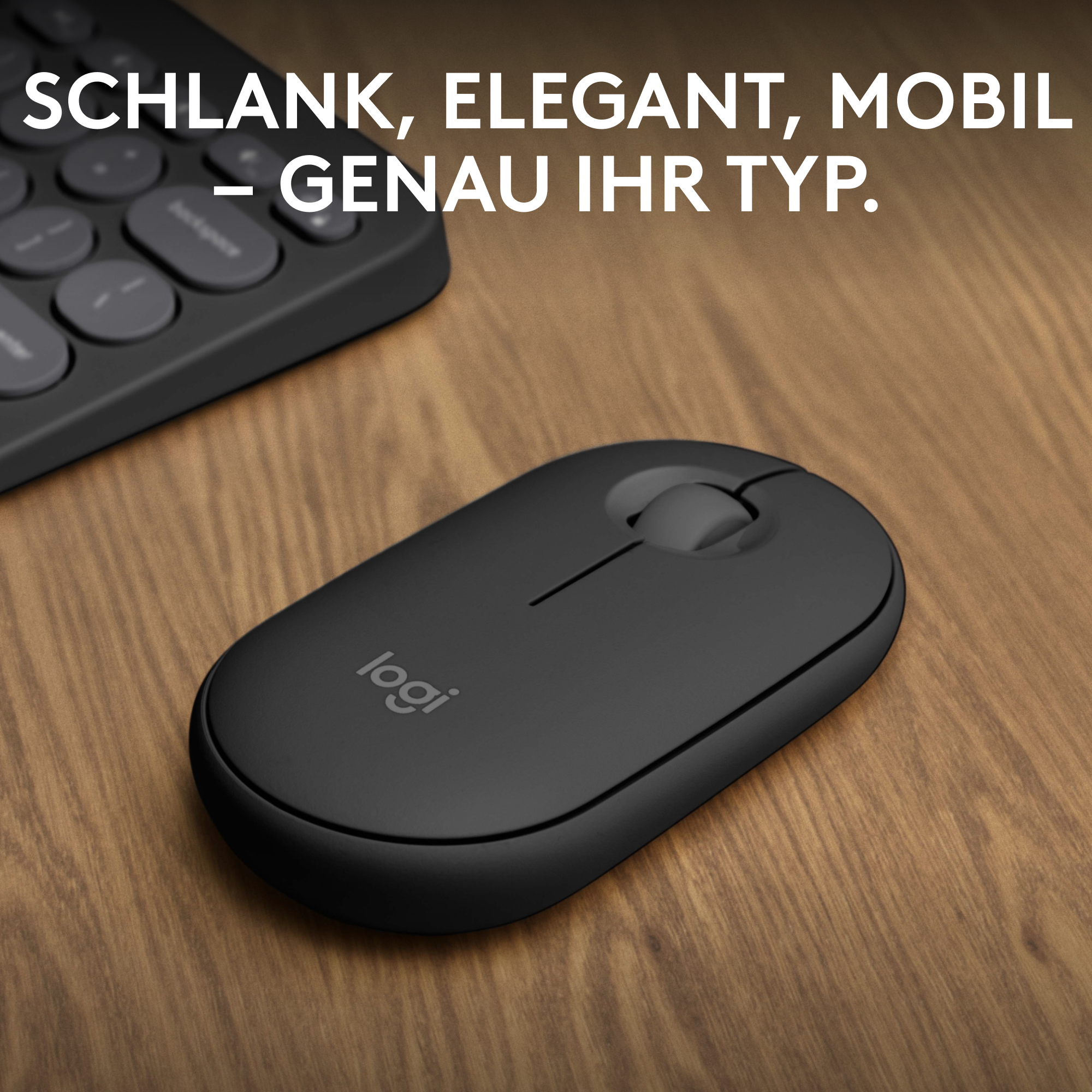 Schwarze Maus auf einem Holztisch mit einer Tastatur im Hintergrund, das Logitech-Logo ist sichtbar.