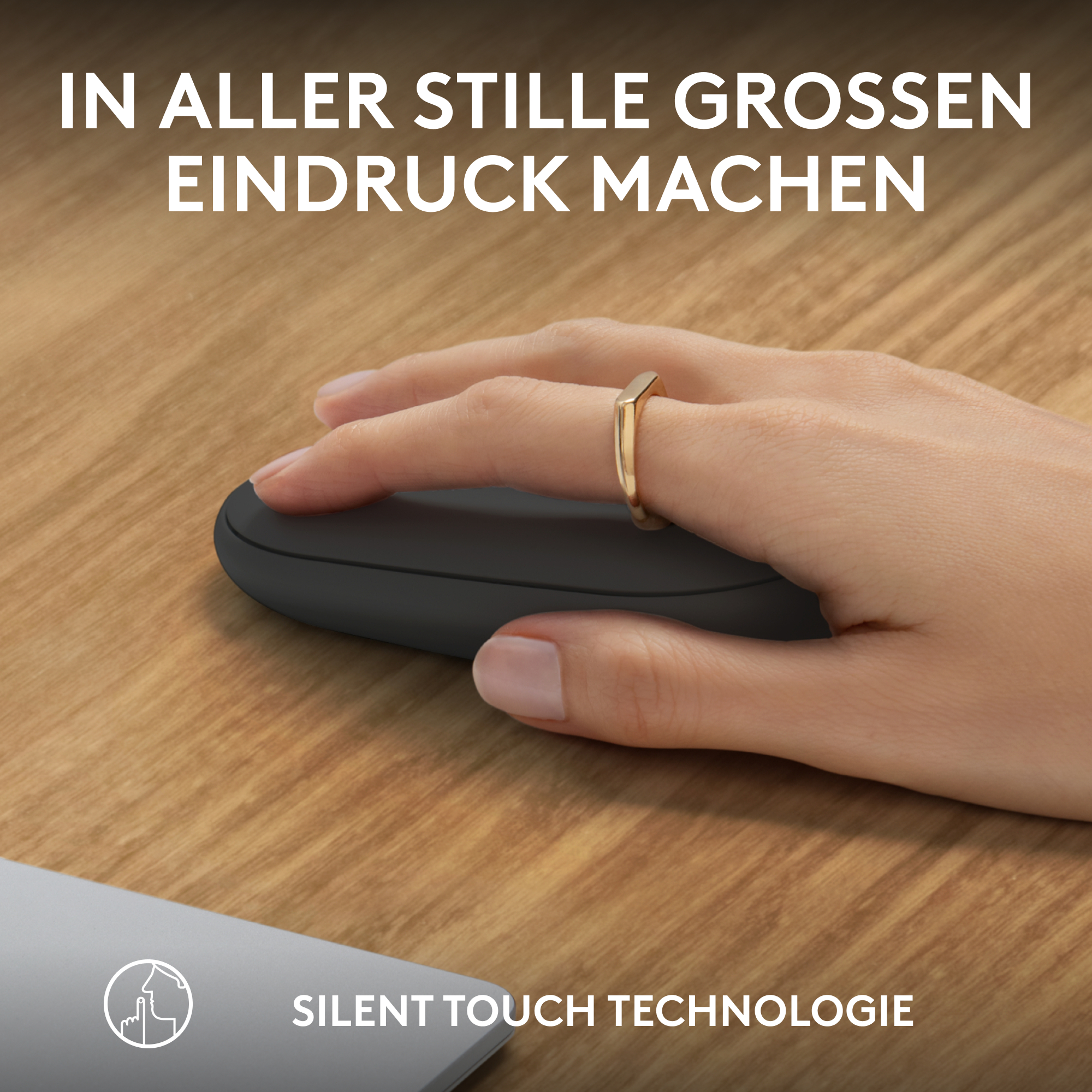 Hand mit Maus, goldener Ring. Text in deutscher Sprache auf Holzoberfläche.