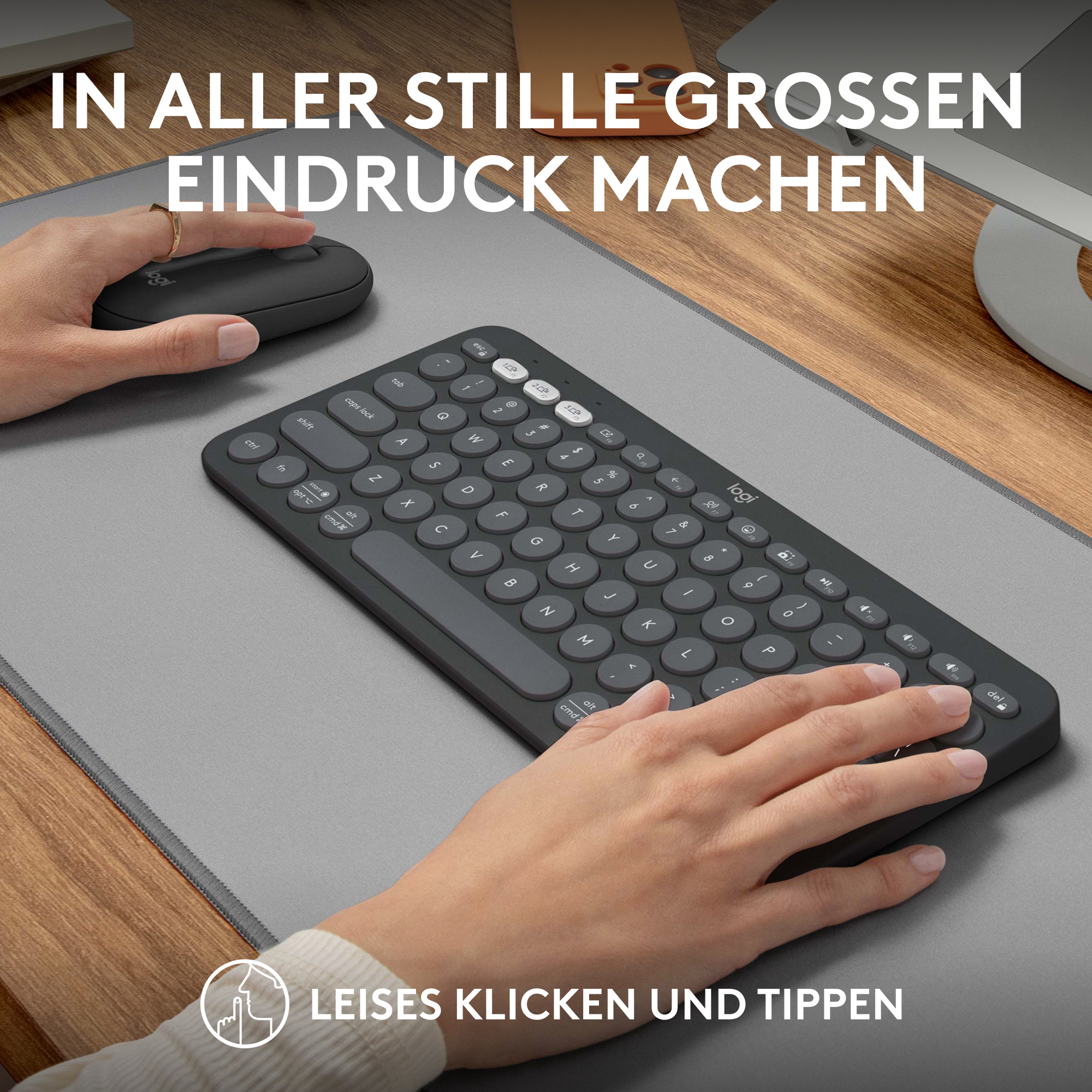 Hände benutzen Tastatur und Maus, graue Matte, Text auf Deutsch.
